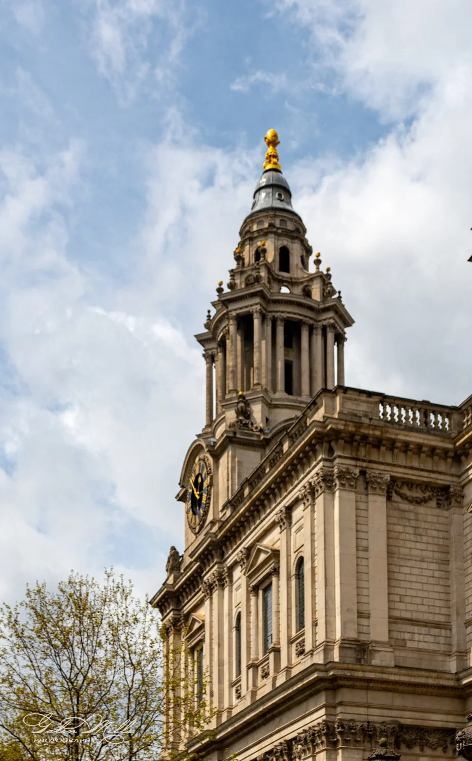 A historic building with a clock tower and ornate architectural details against a cloudy sky.