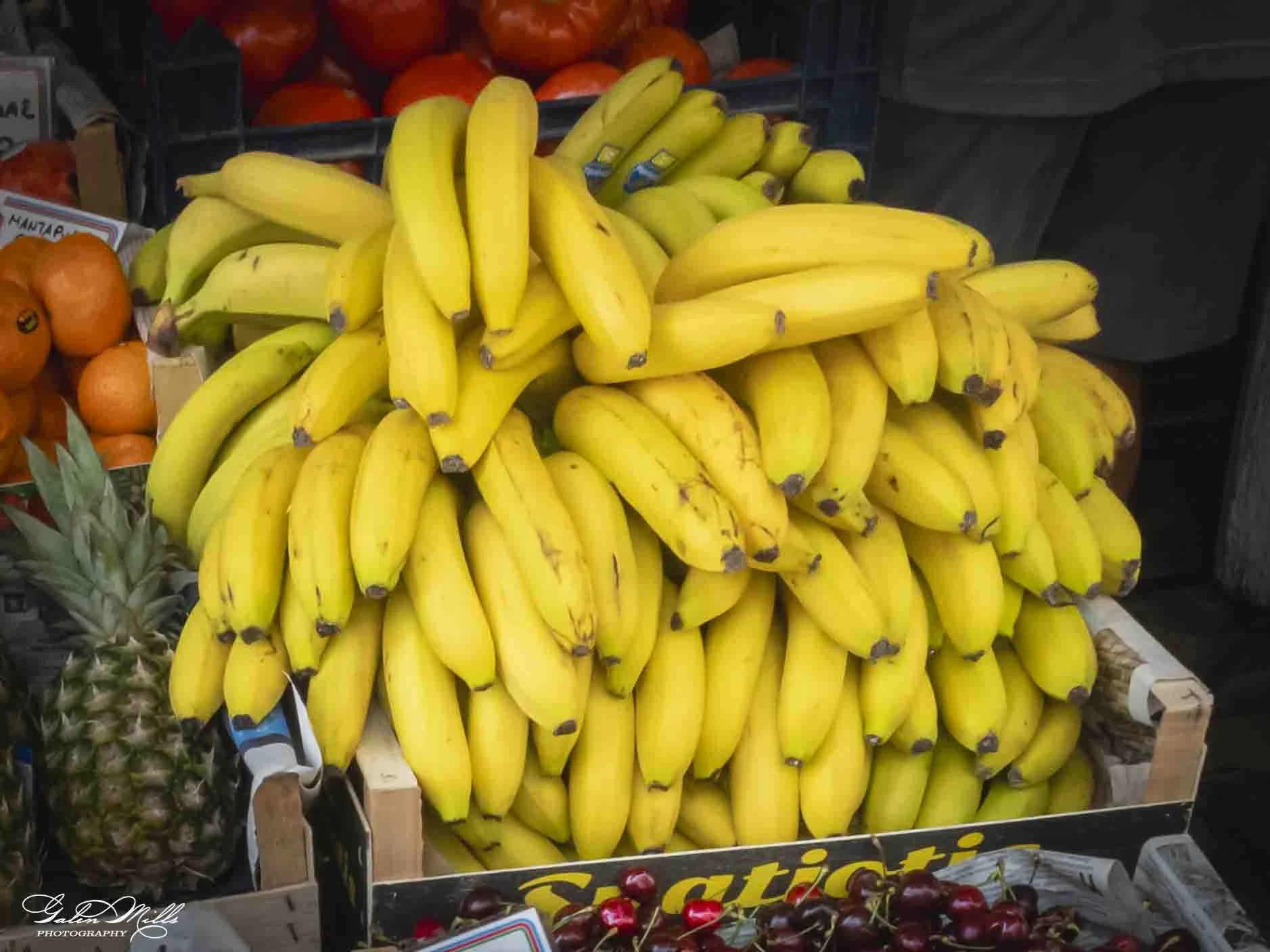 Bunches of ripe yellow bananas arranged on a display shelf at a market.