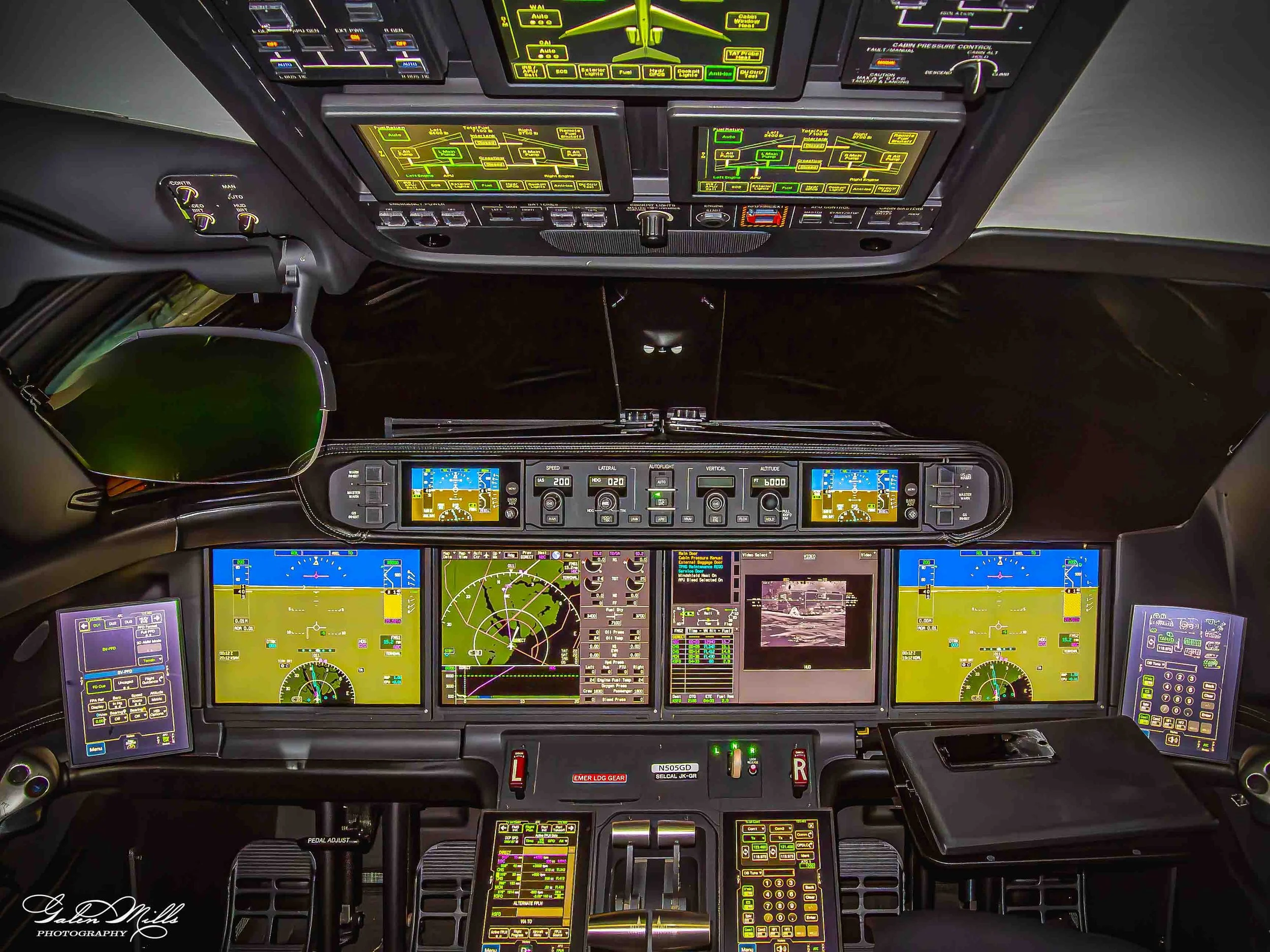 Inside view of an airplane cockpit with multiple screens and controls displaying various flight data, maps, and system information.