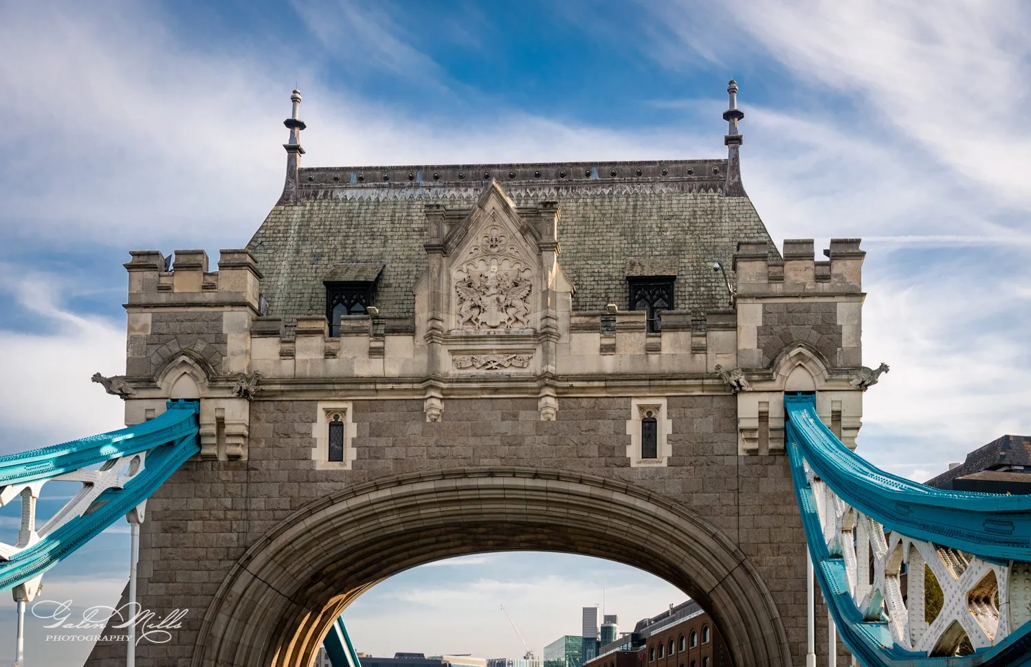Tower Bridge tower with blue suspension cables against a cloudy sky.