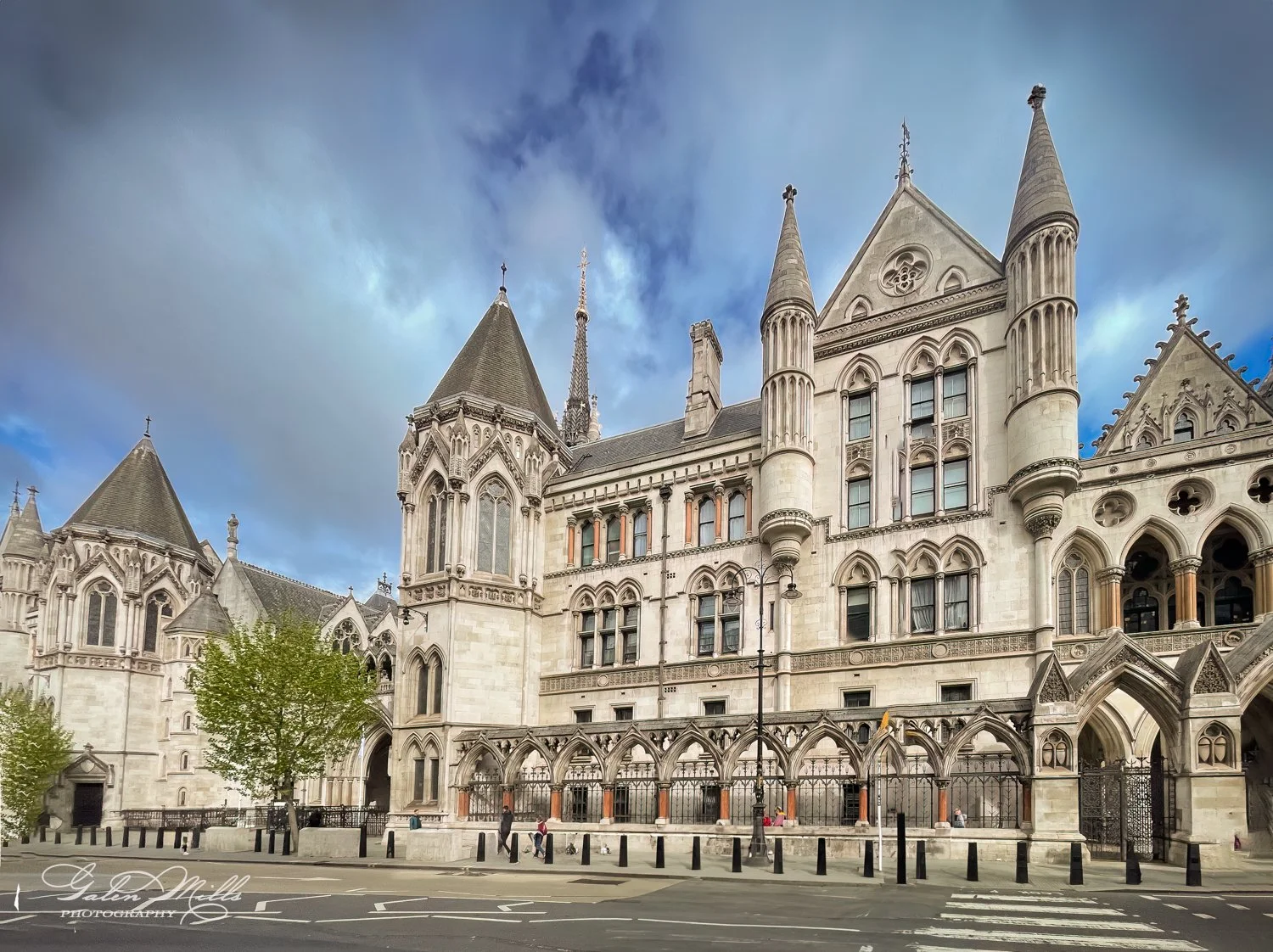 Historic Gothic-style building with pointed towers and arches on a cloudy day.