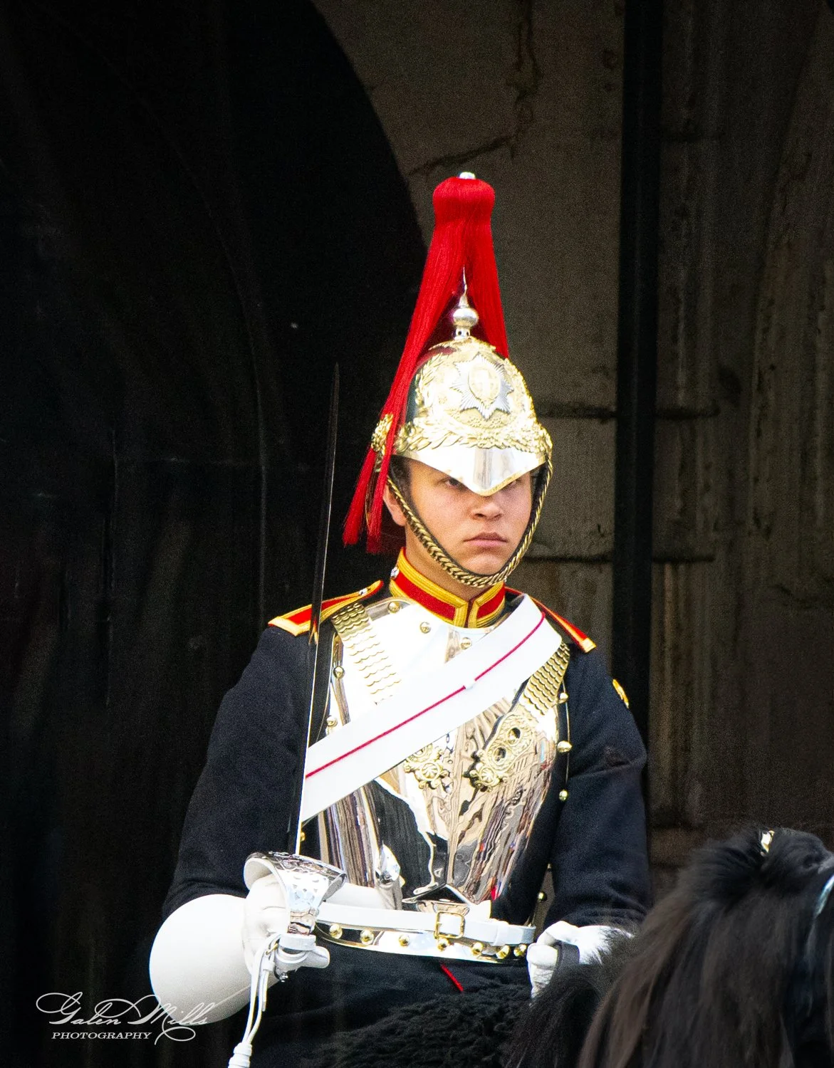 A ceremonial guard in traditional uniform, featuring a red plume and gold helmet, holding a sword.