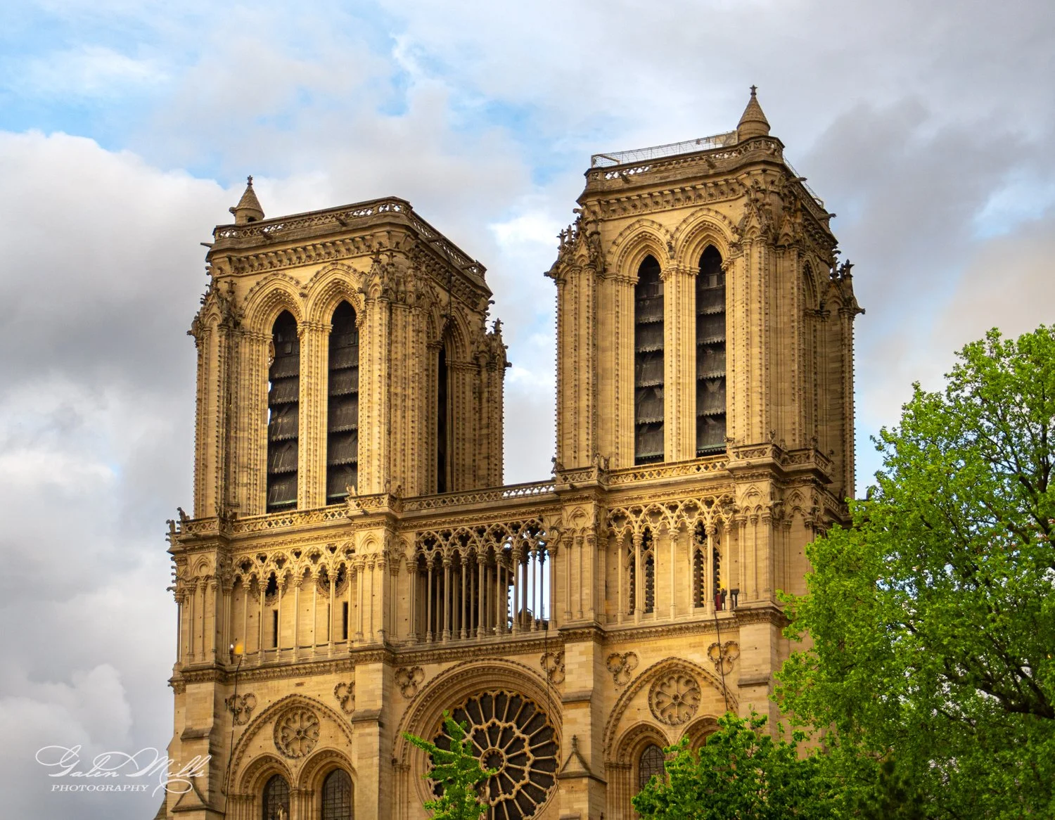 Notre-Dame Cathedral towers against a cloudy sky.