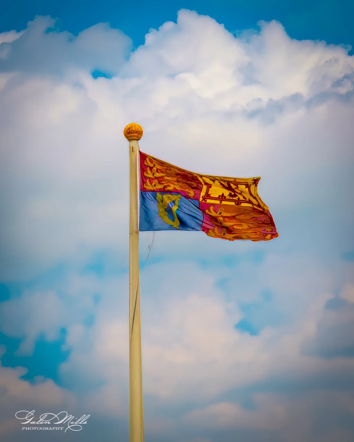 Royal flag of Scotland flying against a cloudy sky.