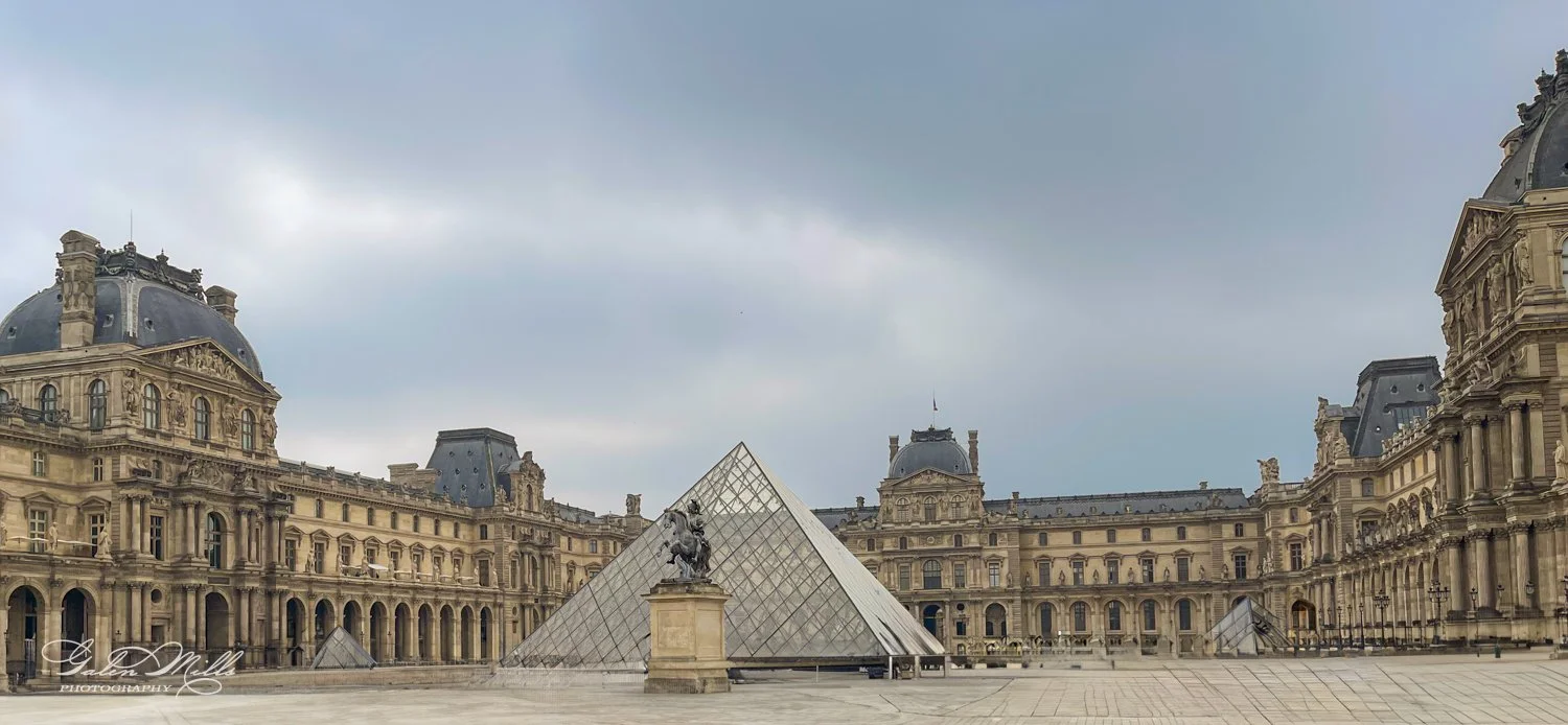 Louvre Museum courtyard with glass pyramid and equestrian statue in Paris.