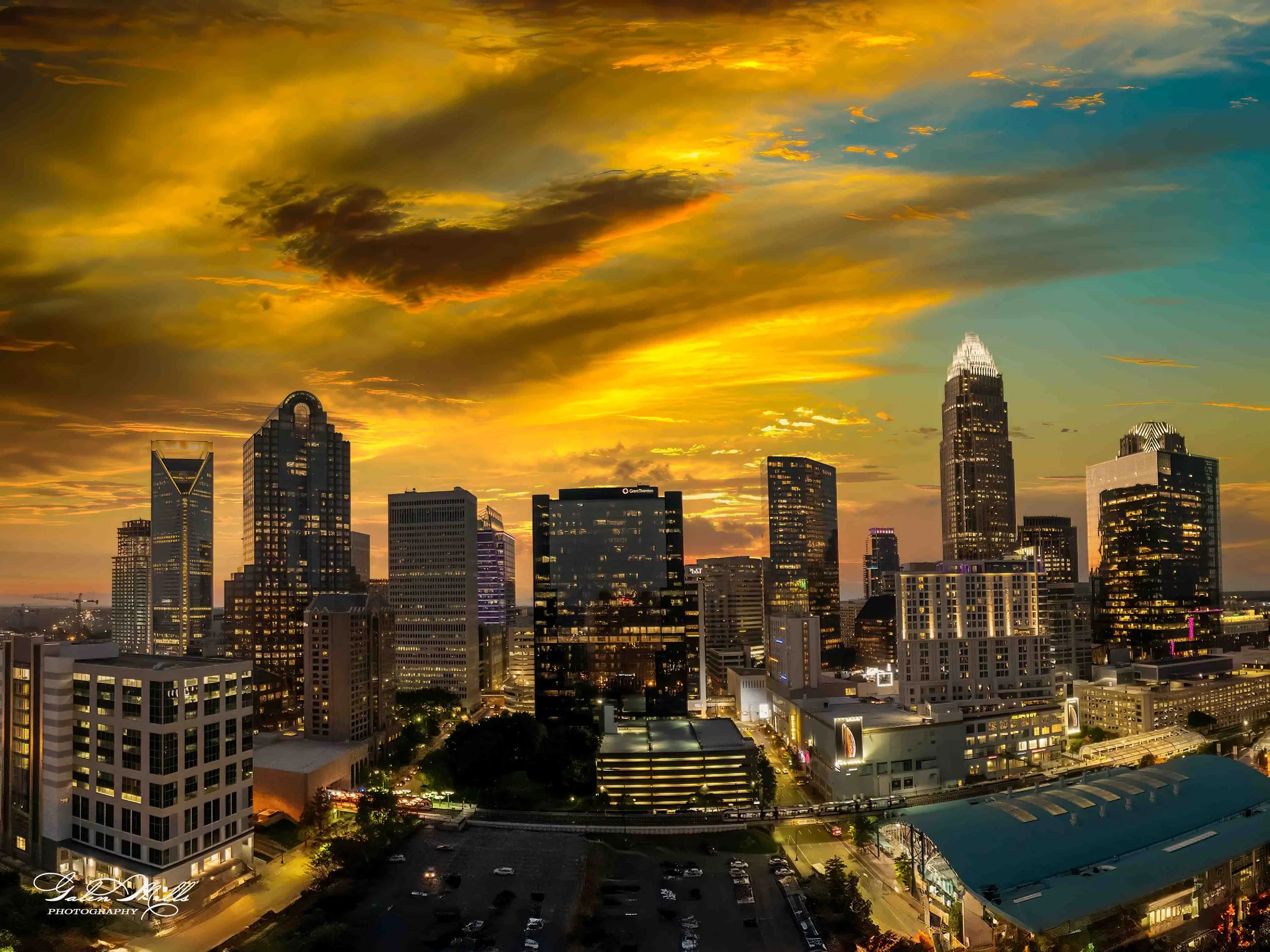 Sunset over a city skyline with tall skyscrapers and clouds in the sky.