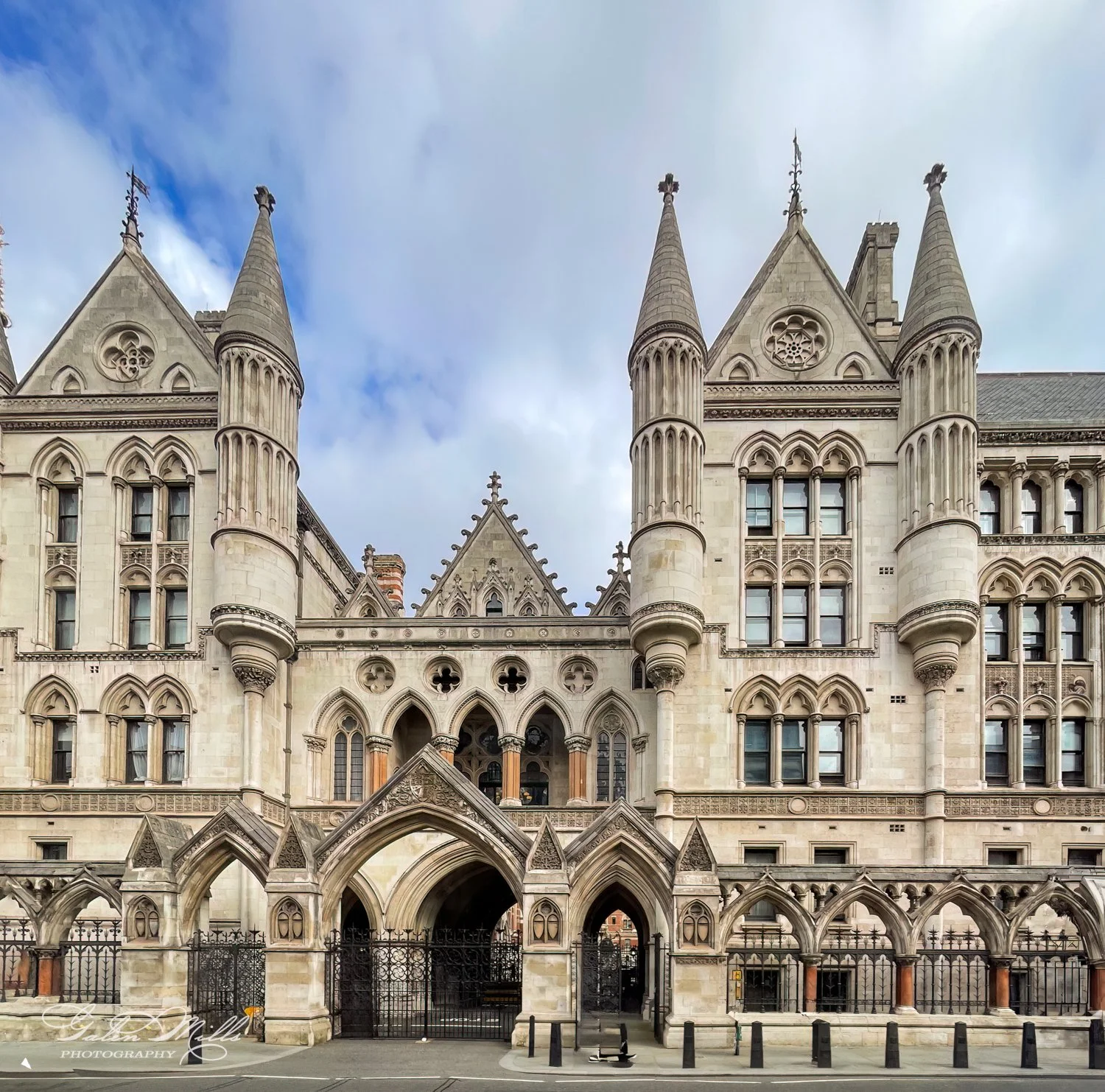 Historic building with ornate Gothic architecture, featuring towers, pointed arches, and intricate stonework. Blue sky background.