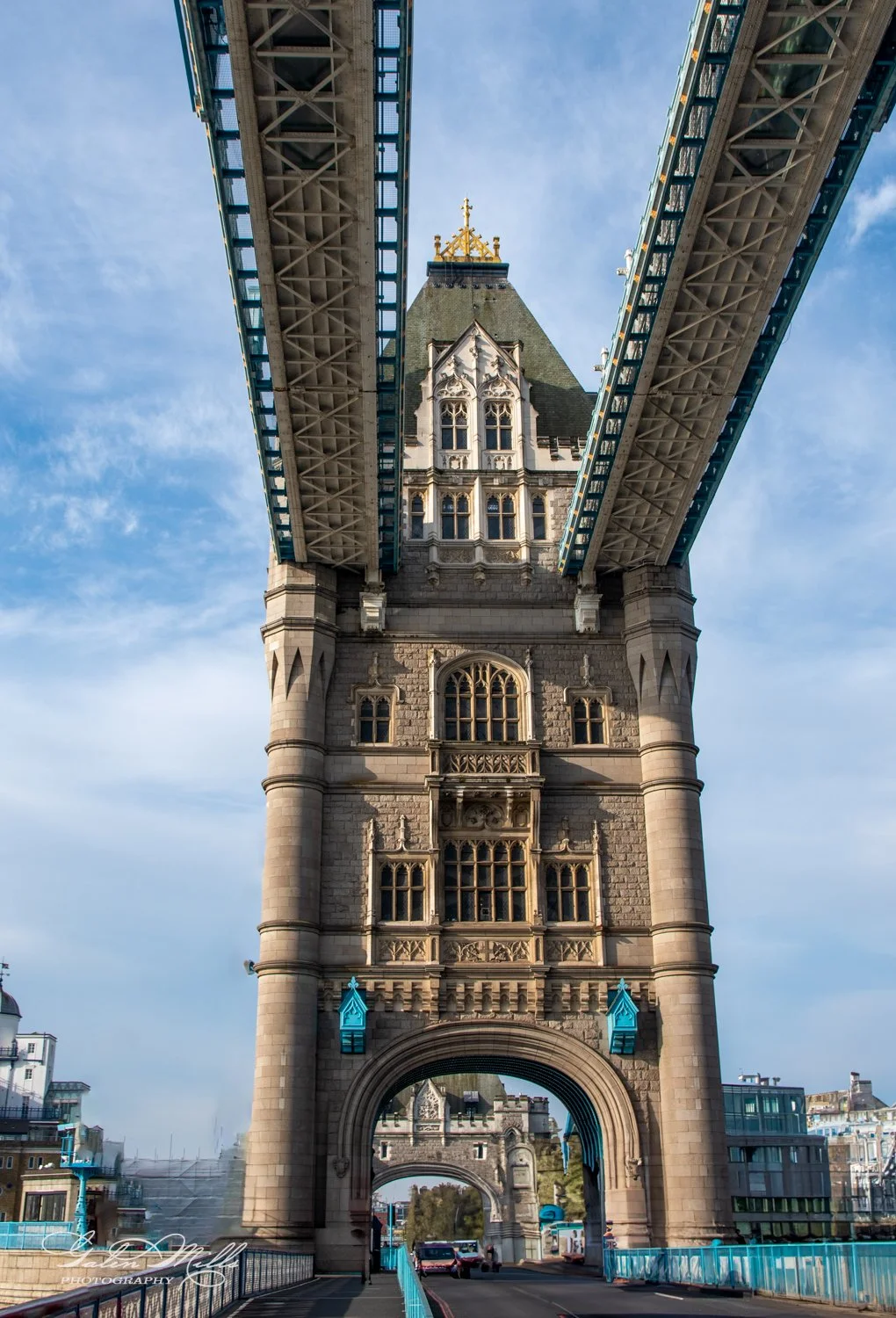 Tower Bridge in London from below, showing the support tower and suspension walkways against a blue sky.
