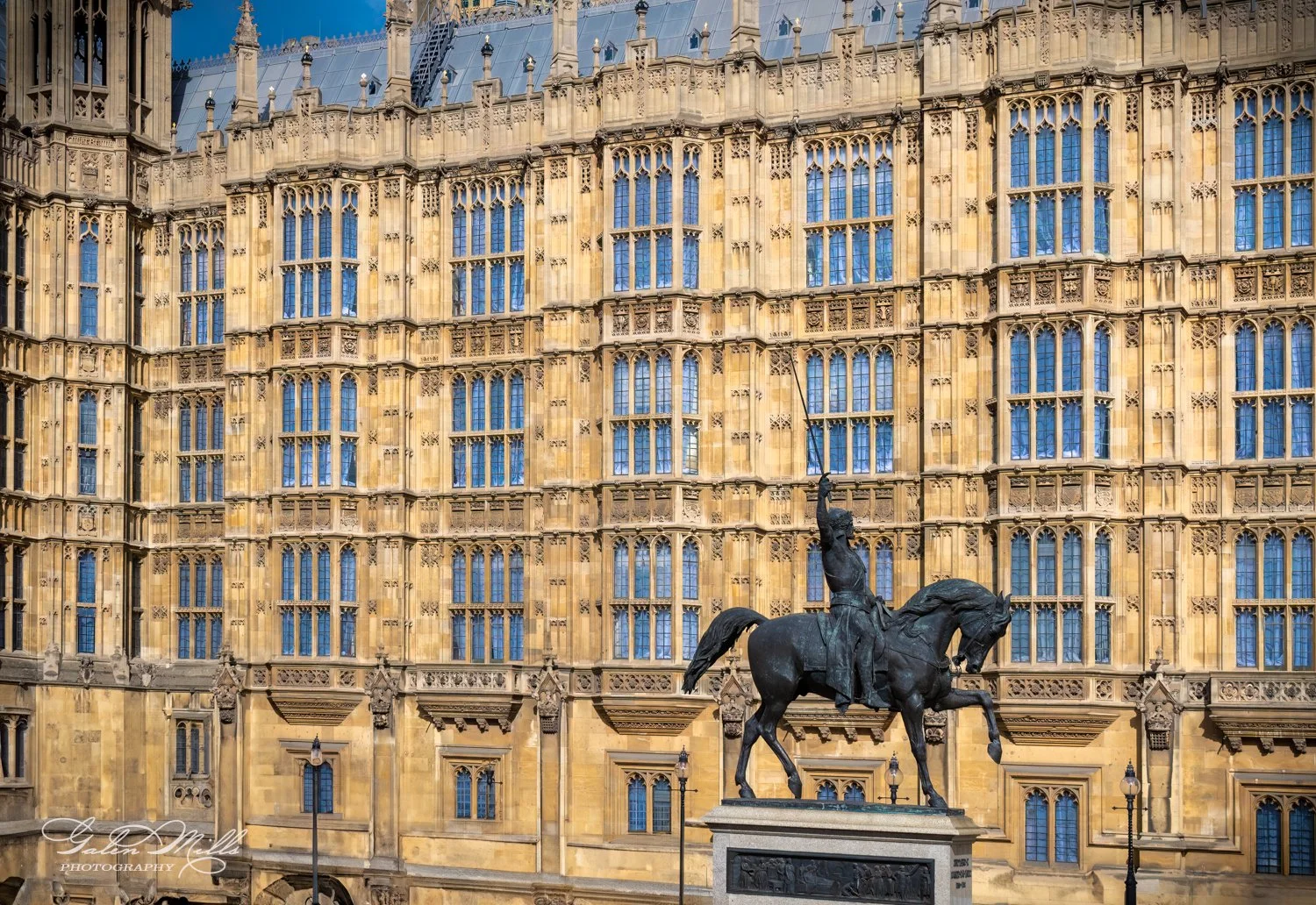 Equestrian statue outside a Gothic-style building, with detailed architecture and numerous windows.