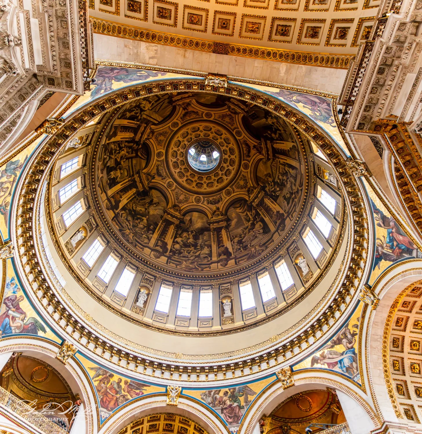 Intricately decorated domed ceiling with paintings and arches.