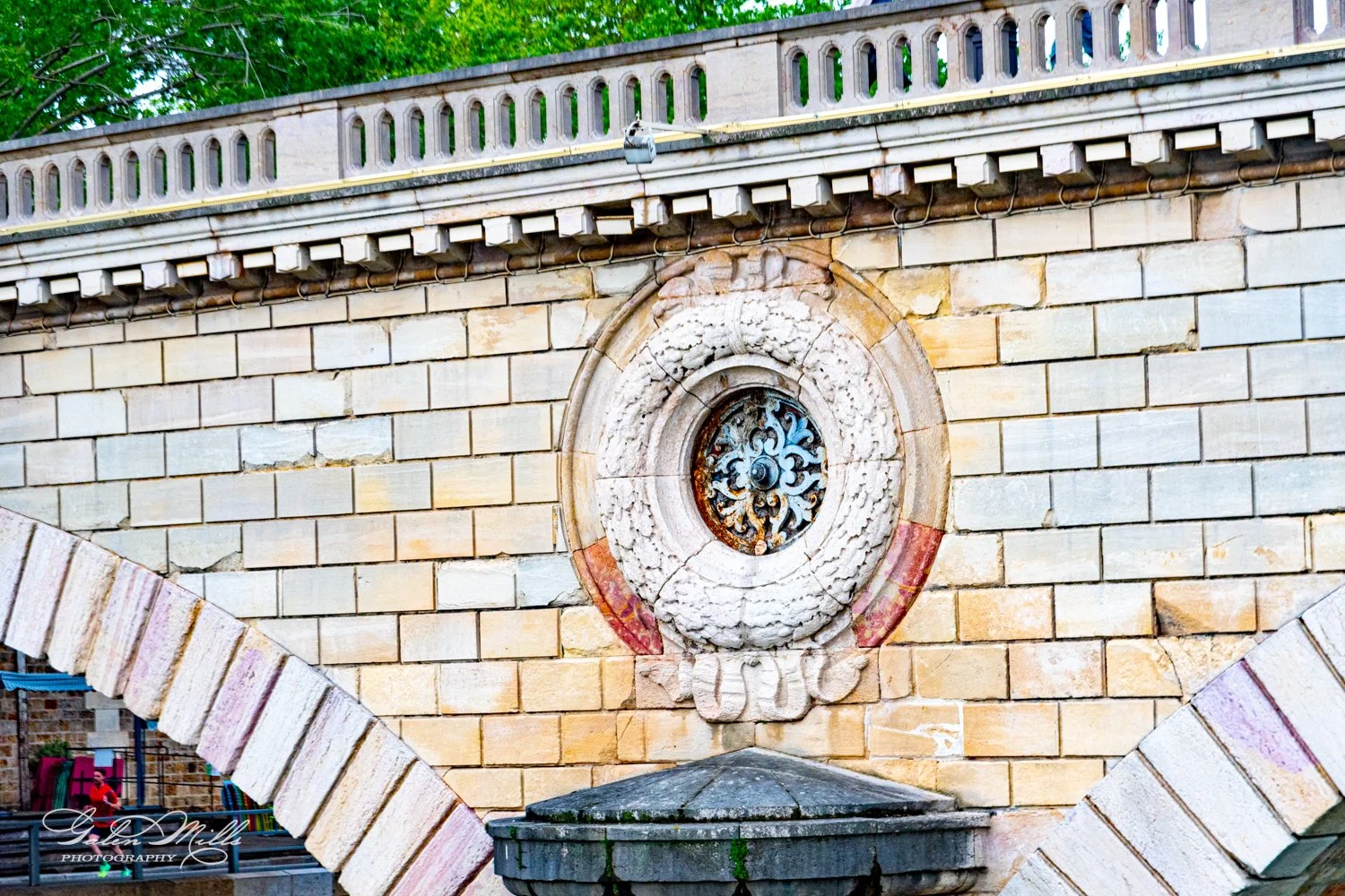 Ornate stone wall with circular decorative window and iron grille.