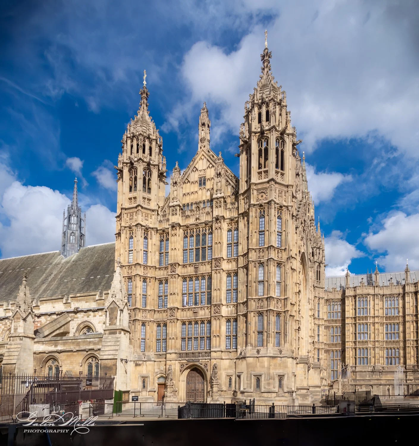 Gothic architecture of the Palace of Westminster in London under a blue sky with clouds.