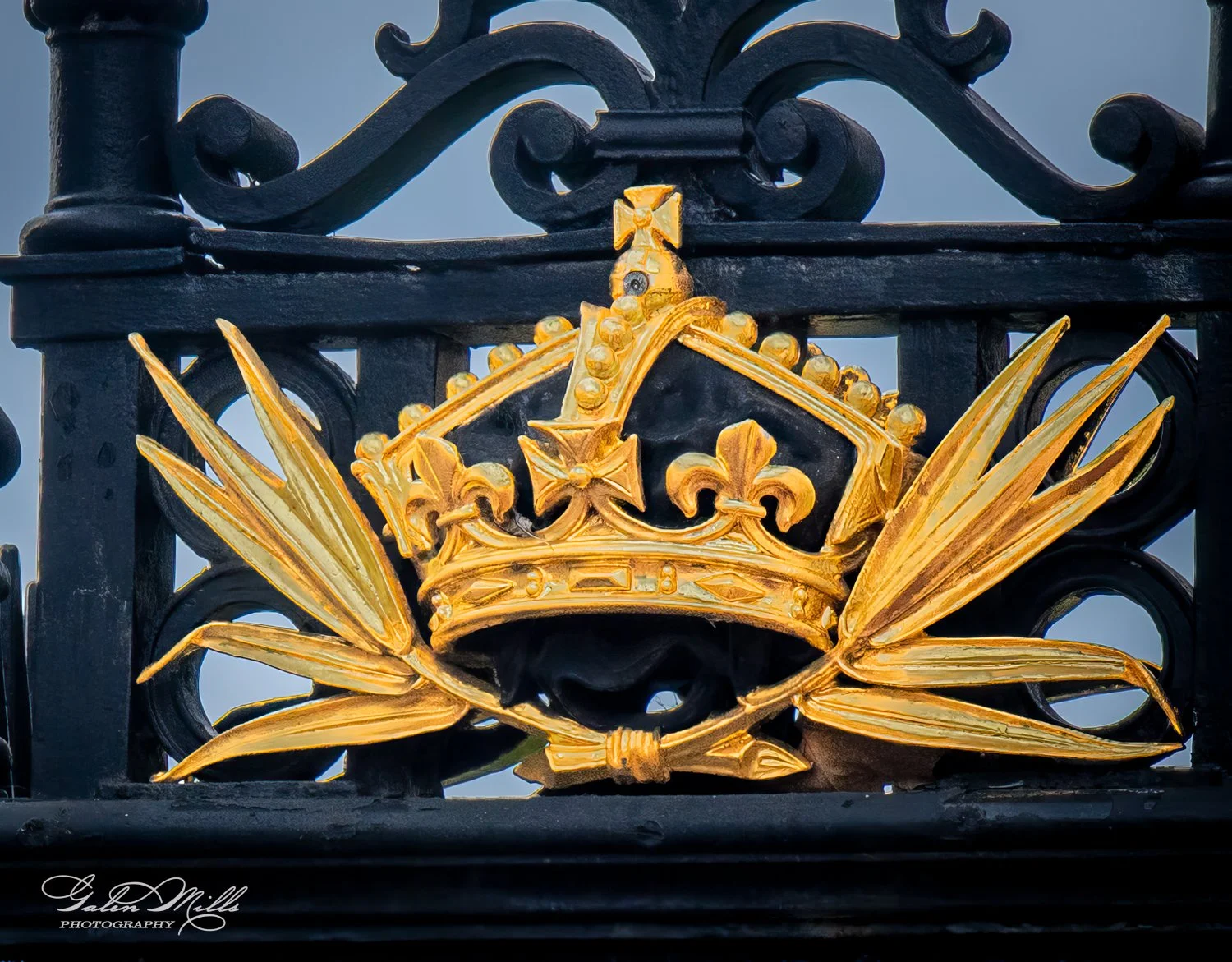 Ornate black and gold metal crown design on a gate.
