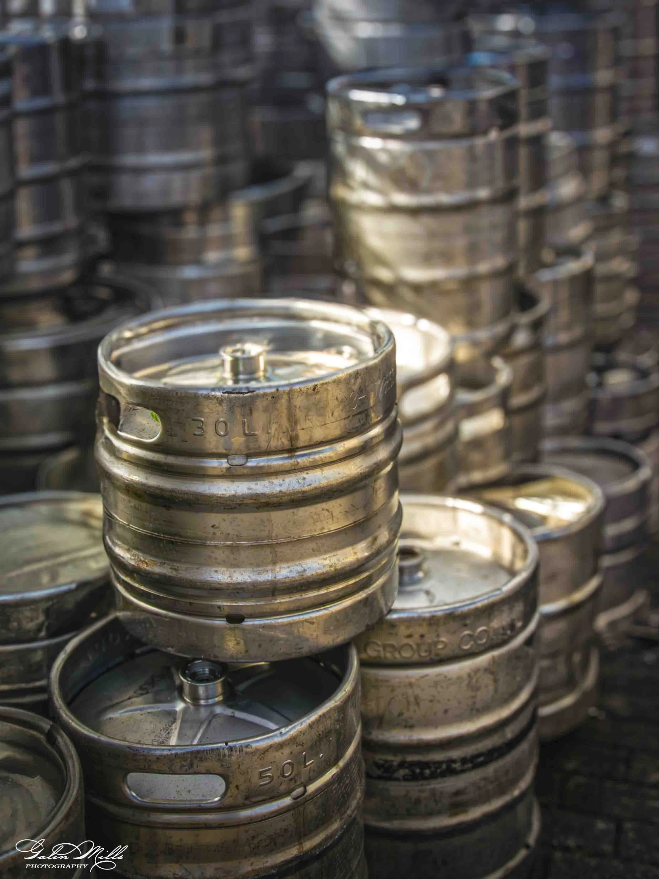 Multiple stacked empty metal cans, labeled 5.0L, with some rust and dirt.