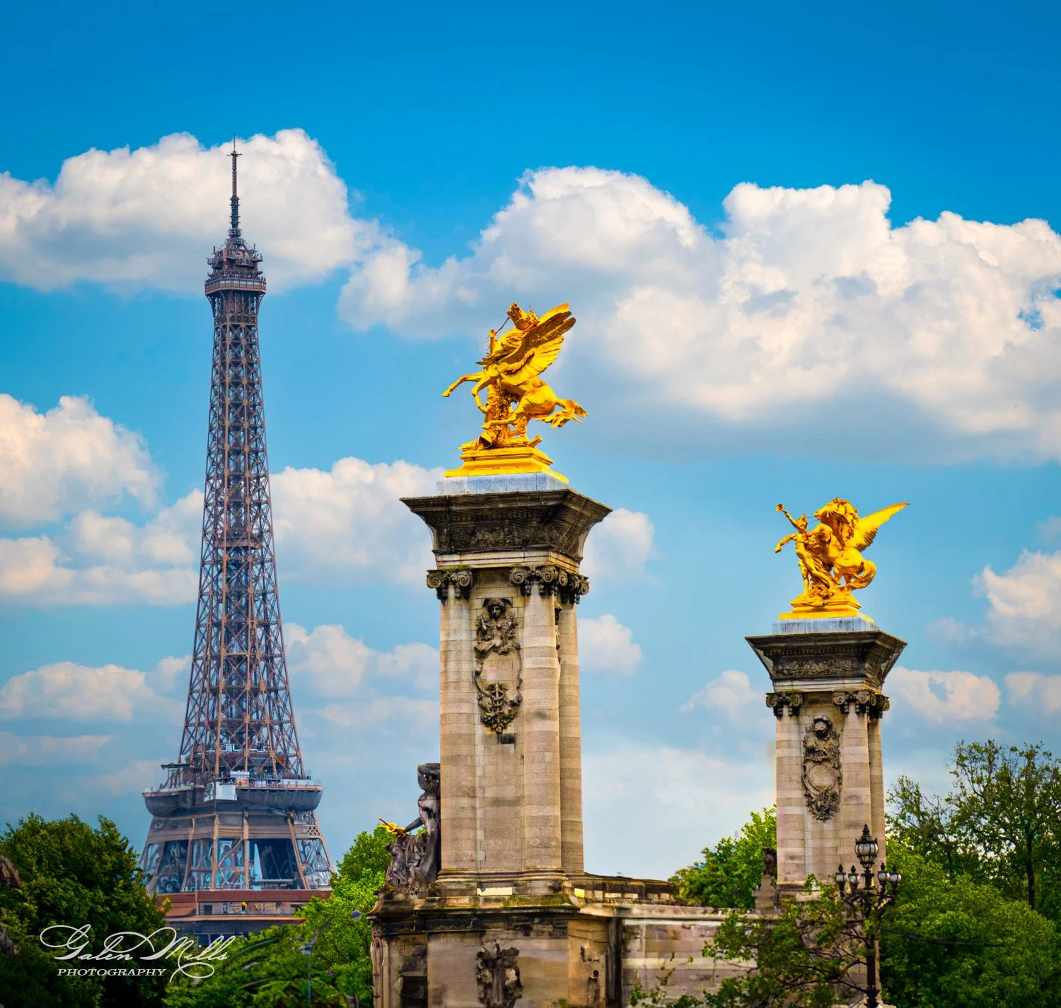View of the Eiffel Tower behind the golden statues on the Pont Alexandre III bridge in Paris.