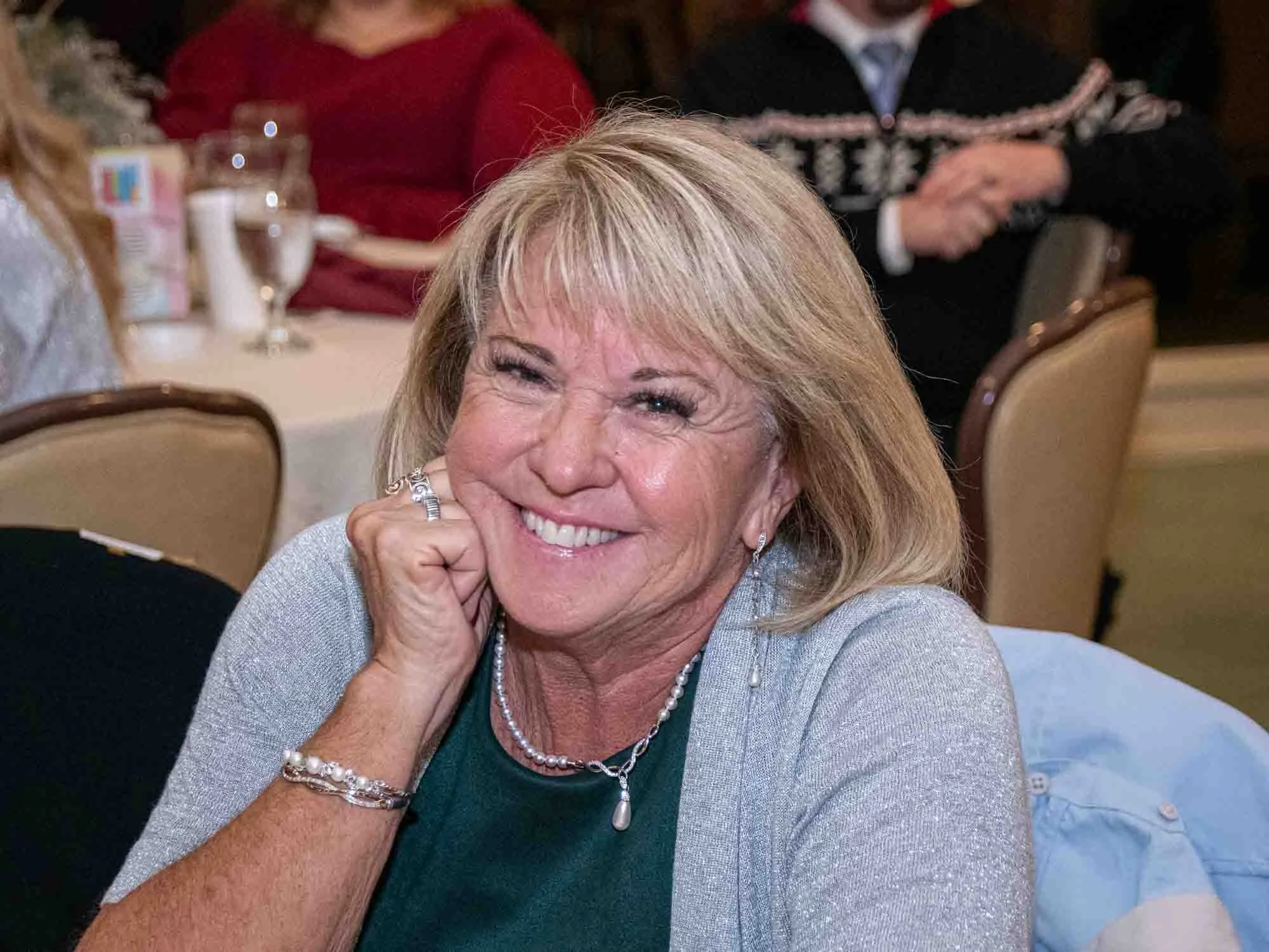 Smiling woman sitting at a table during an event.