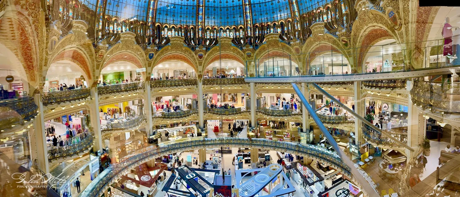 Interior of an ornate, multi-level shopping mall with decorative glass dome ceiling.