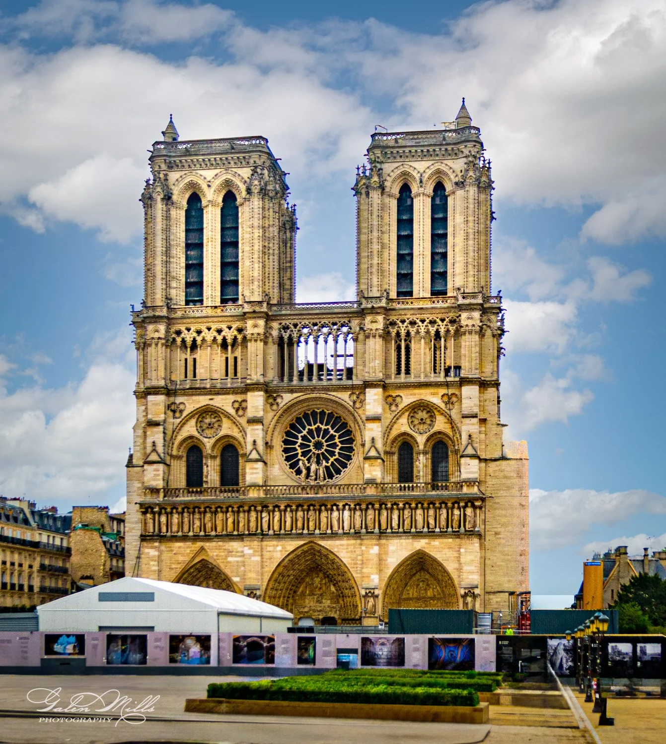 Notre-Dame Cathedral in Paris, featuring Gothic architecture with twin towers and a rose window, under a partly cloudy sky.