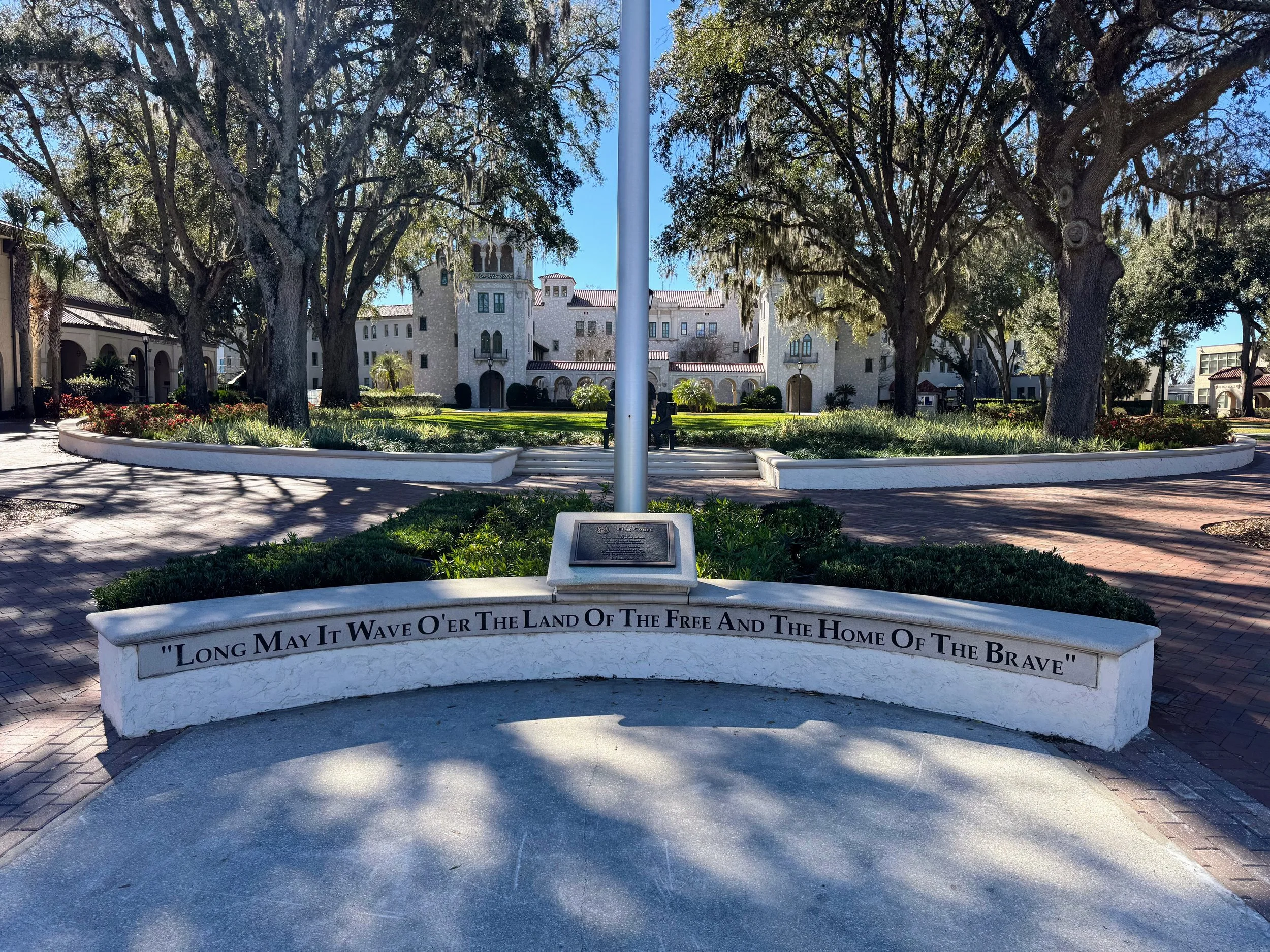 Flag pole sign at The Bolles School with wall cap. Steps and circular seating around green space with wall cap.