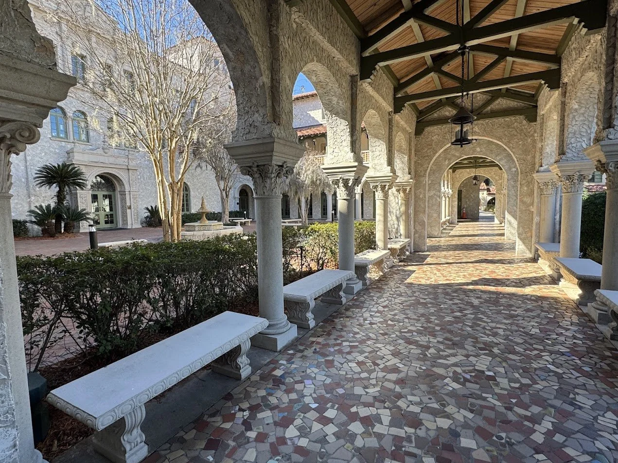 Precast benches along the outdoor hall flanked by columns.