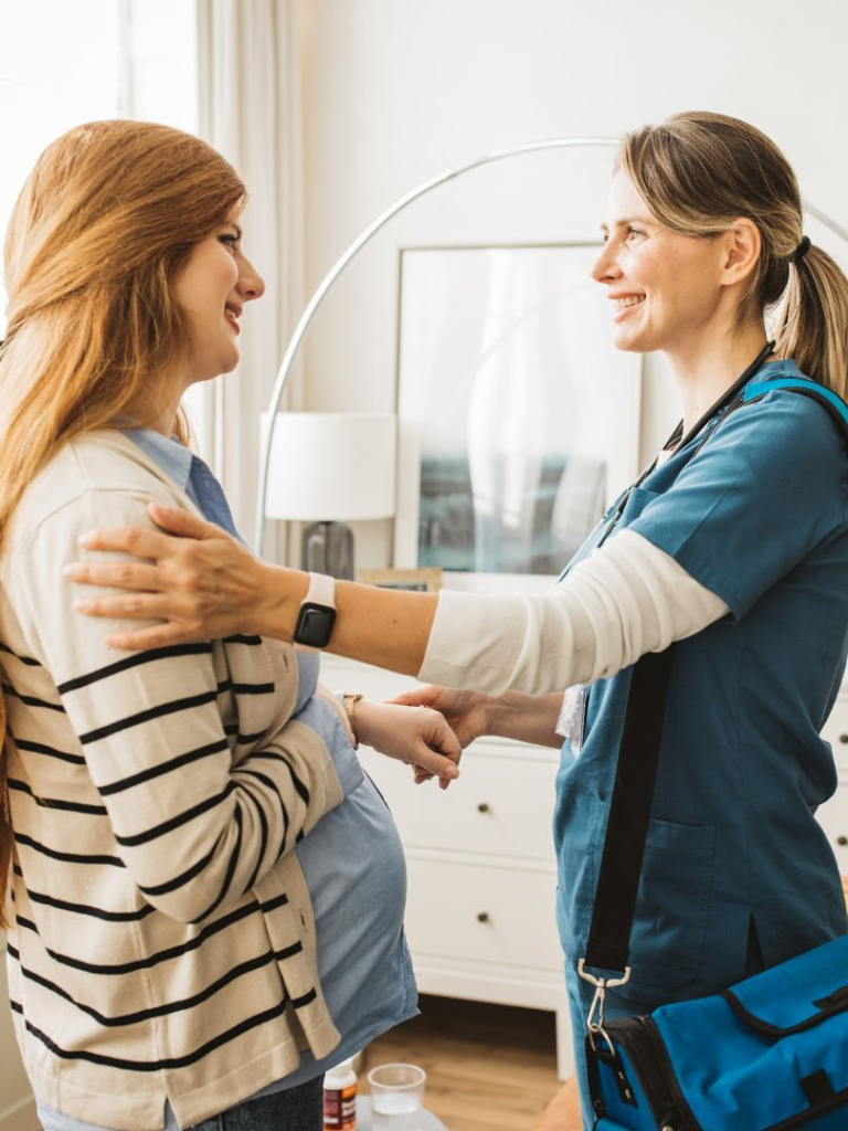 Pregnant woman talking with female healthcare professional in a clinic room.