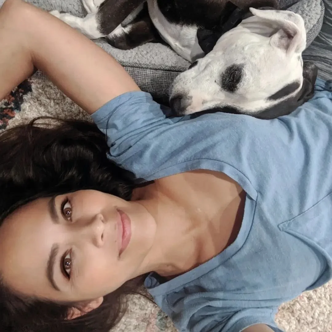 A woman lying on the floor with a black and white dog resting its head on her chest, both appearing relaxed and comfortable.