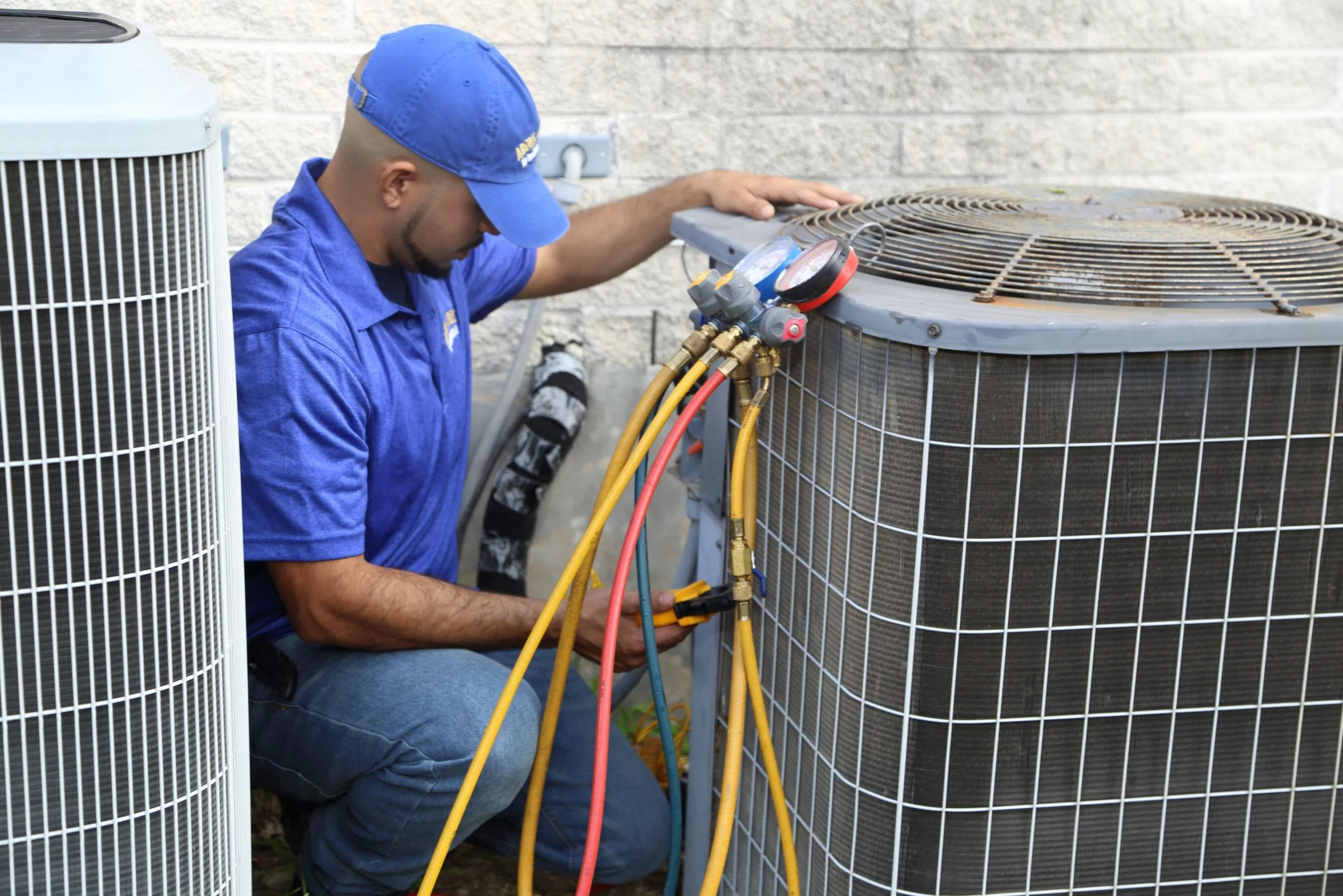 HVAC technician checking an outdoor condenser with manifold gauges