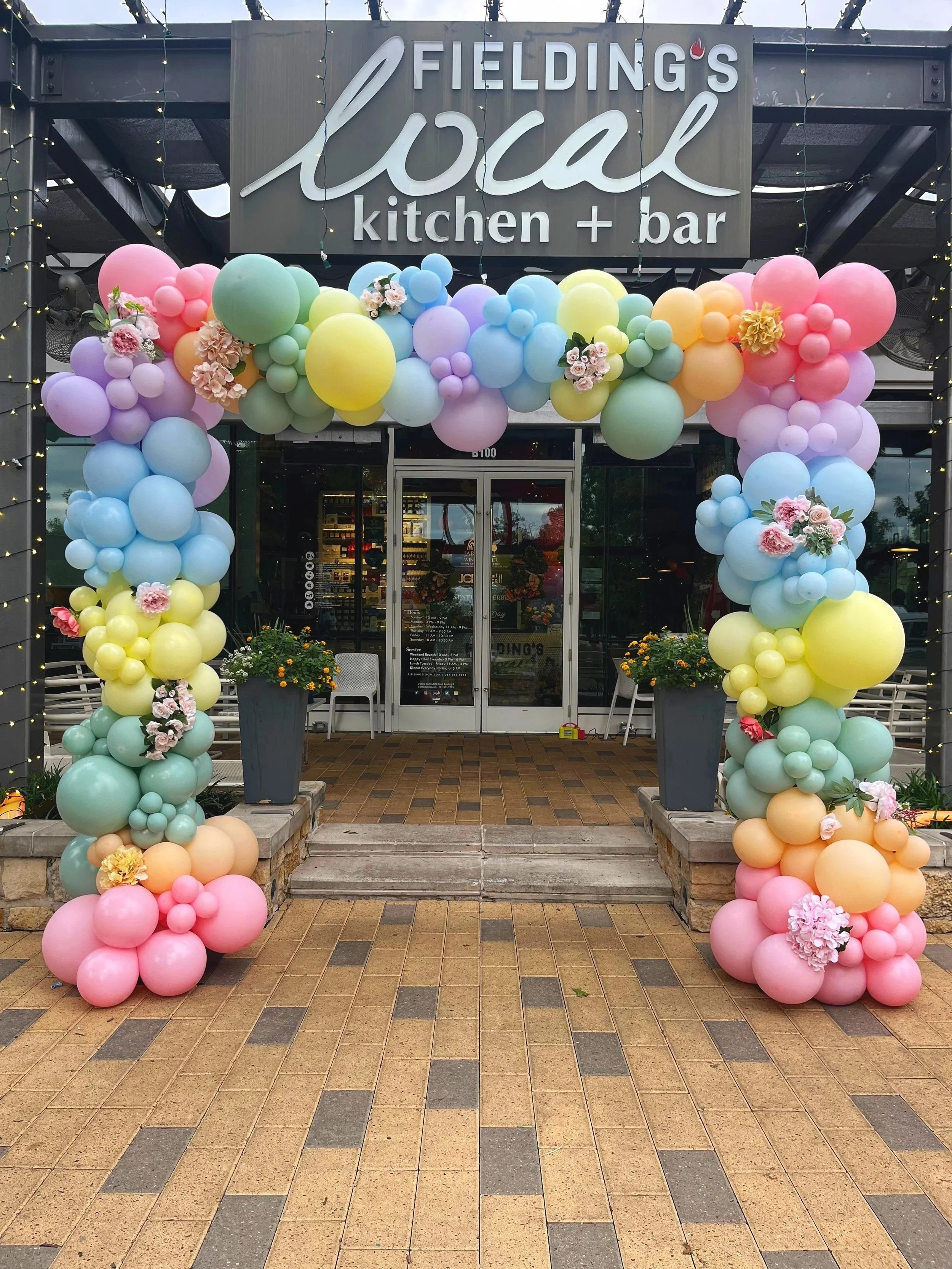 Pastel rainbow organic balloon arch at a restaurant entrance, The Woodlands