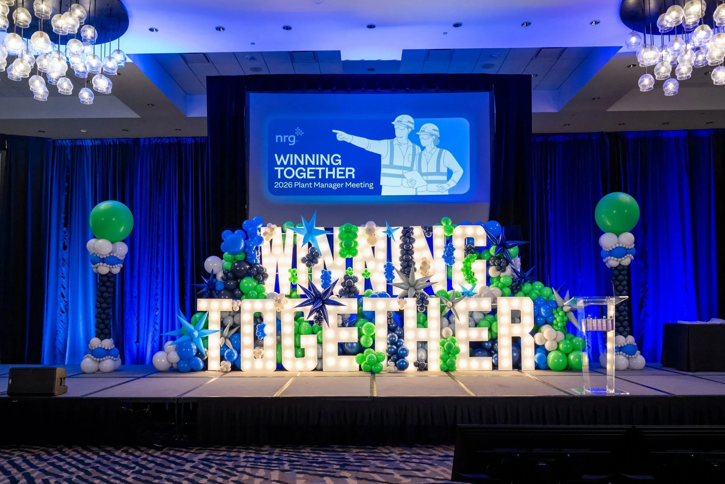 Corporate stage with light-up marquee letters and green and blue balloons, The Woodlands