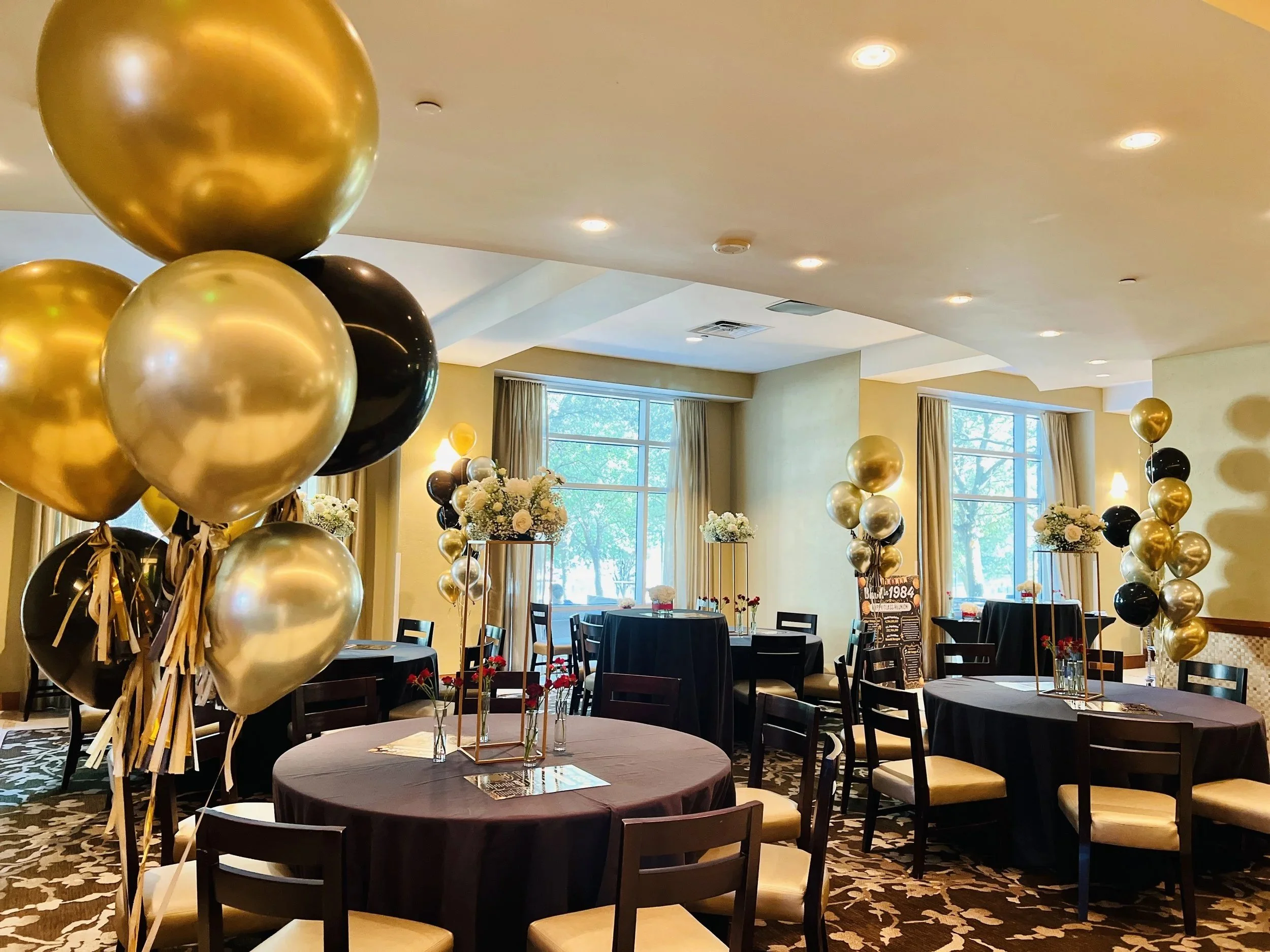 Jumbo gold and black balloon centerpieces across an elegant dining room, The Woodlands