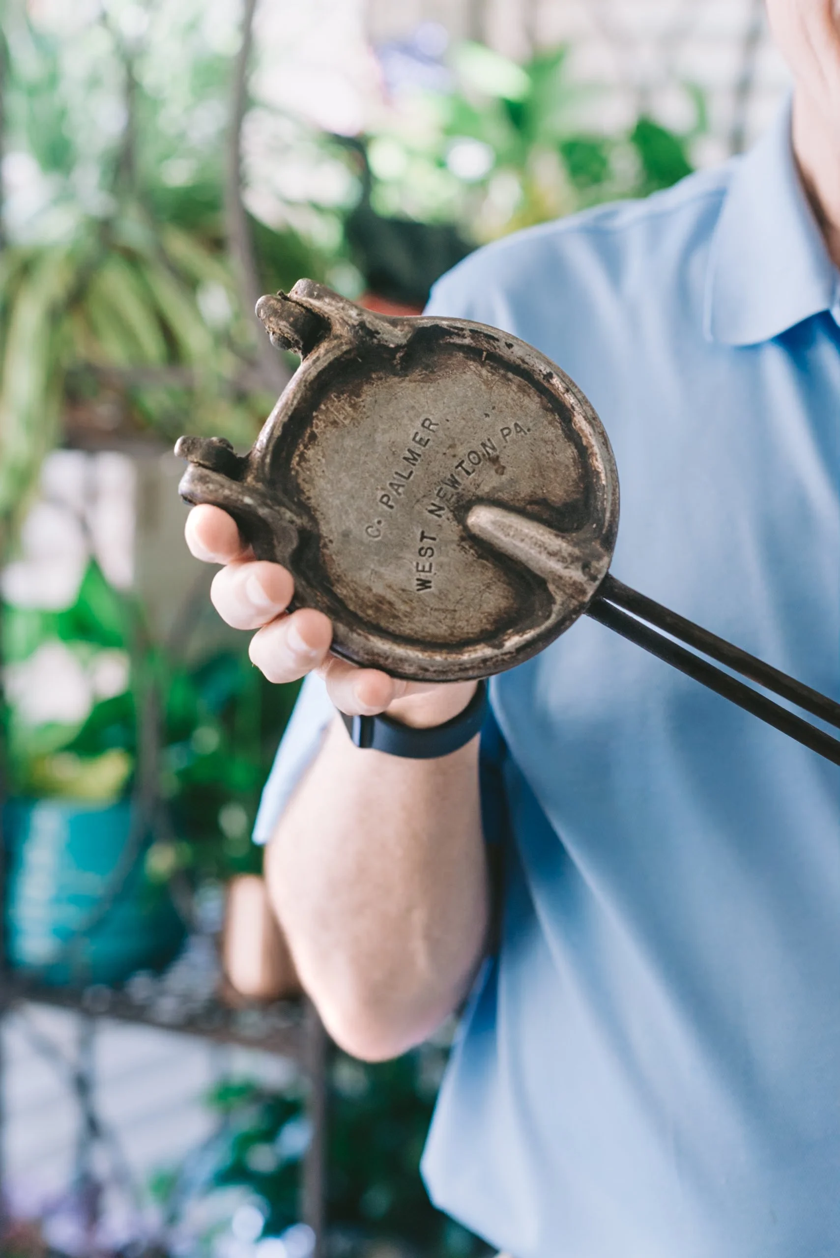 Person holding a vintage metal garden trowel with the inscription 'G. PALMER, WEST NEWTON PA.'