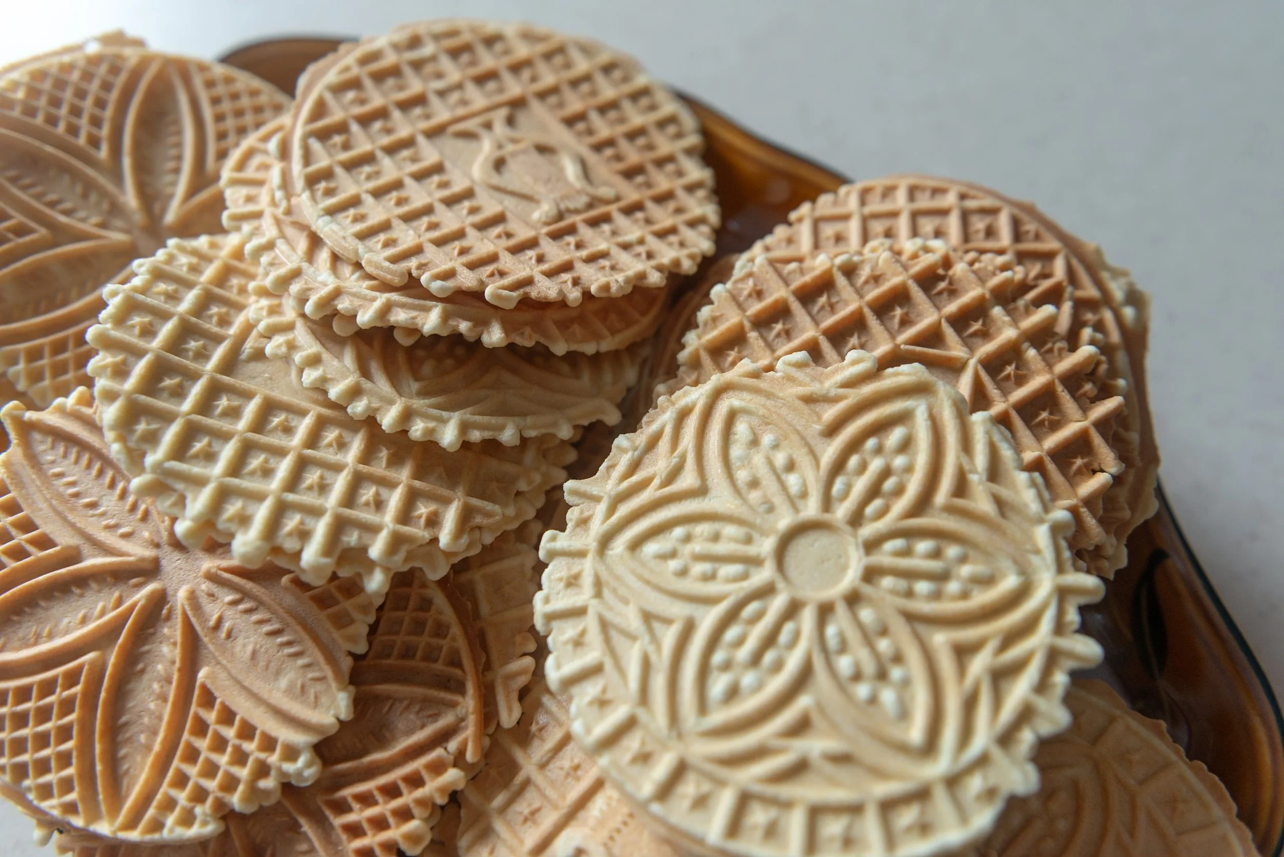 Assorted patterned waffle cookies in a bowl.