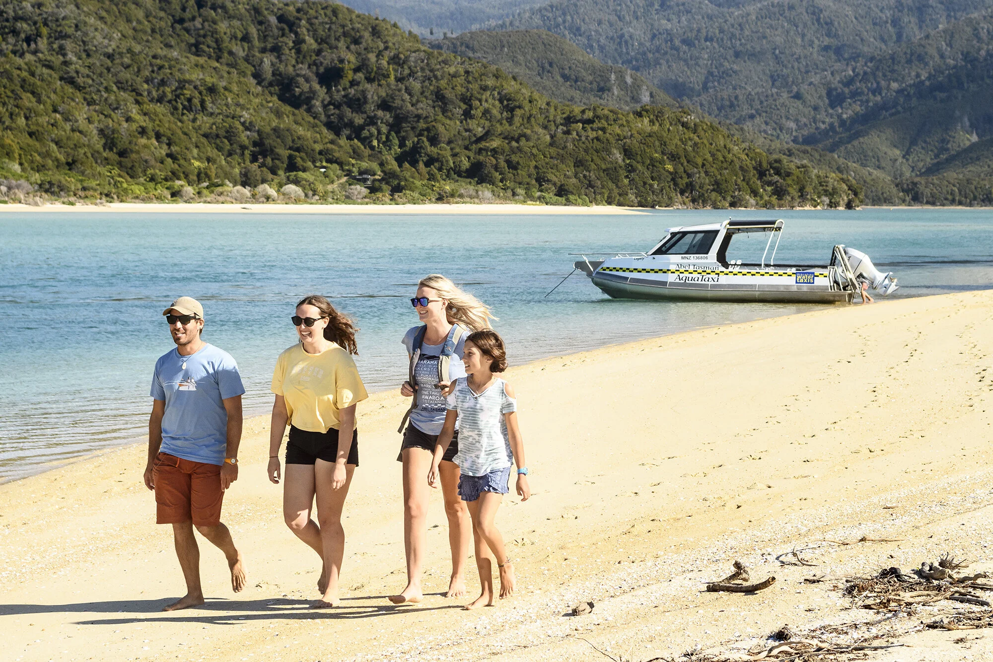 Four people walking on the beach in Abel Tasman