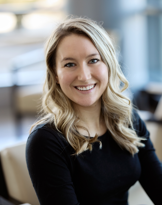 A smiling woman with blonde hair in an office setting.