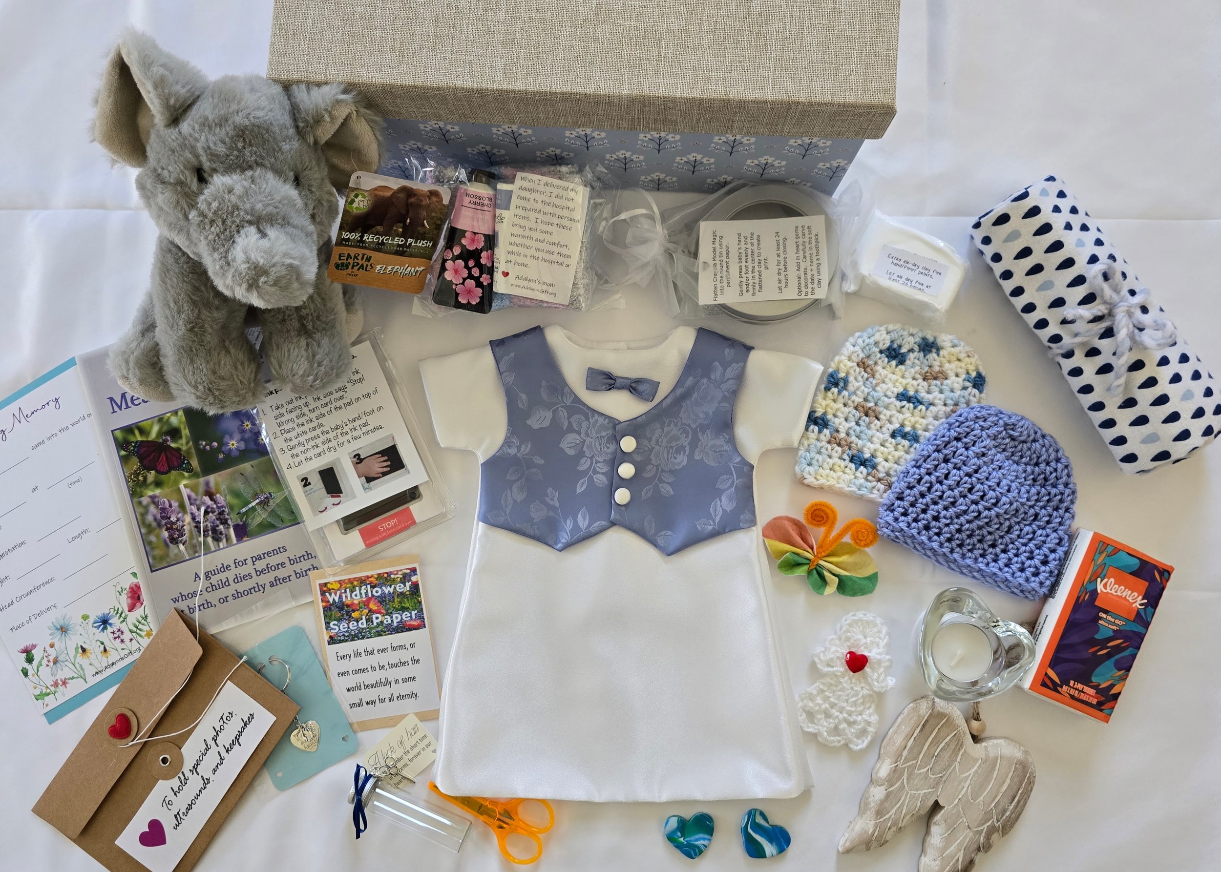 Collection of baby girl items including a pink plush bunny toy, a floral box, a glass with a cartoon character, a guidebook, a floral hairband, a pink lace dress, crocheted blankets, a crocheted hat, a package of wipes, a pair of pink butterfly earrings, a beaded bracelet, and a greeting card with a floral design.