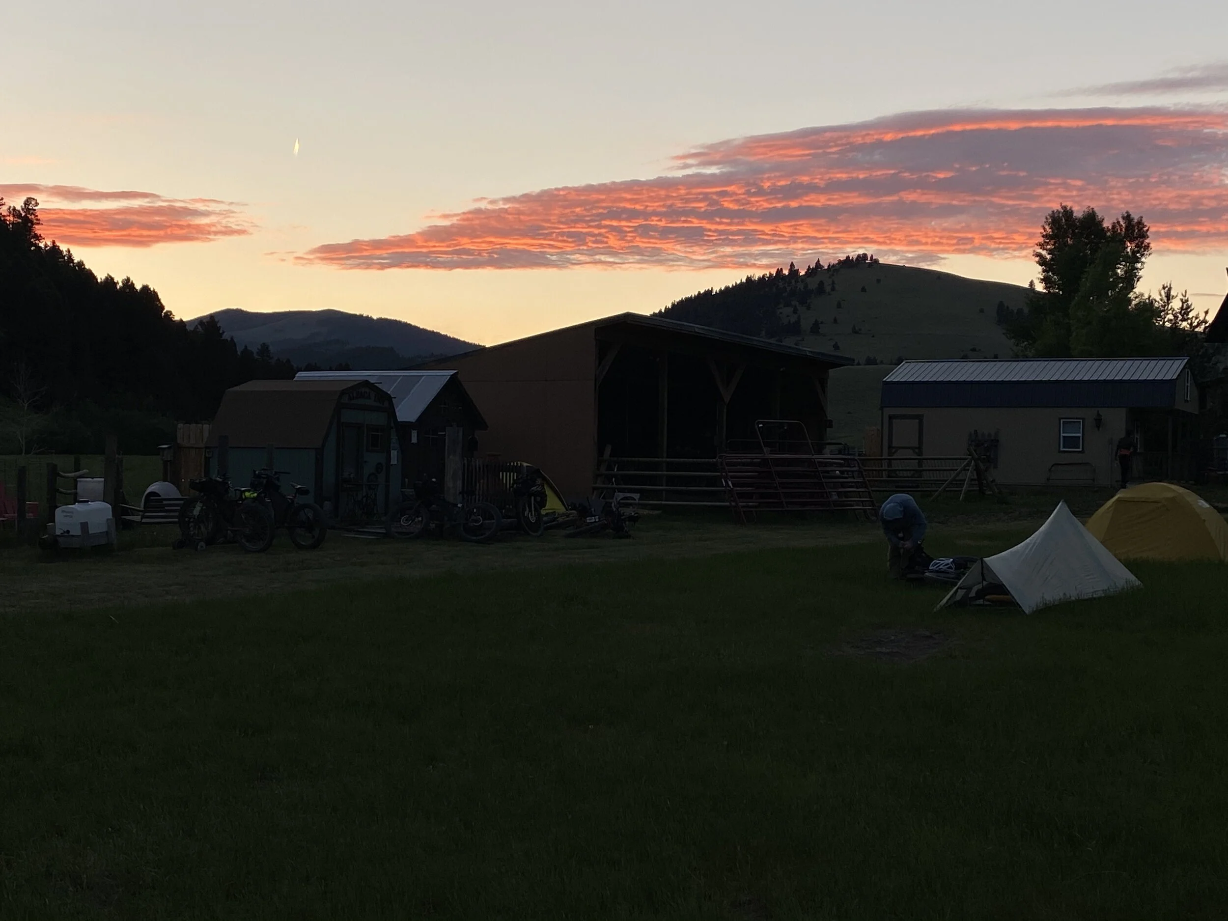 A couple of tents and out buildings in the meadow of the lodge.