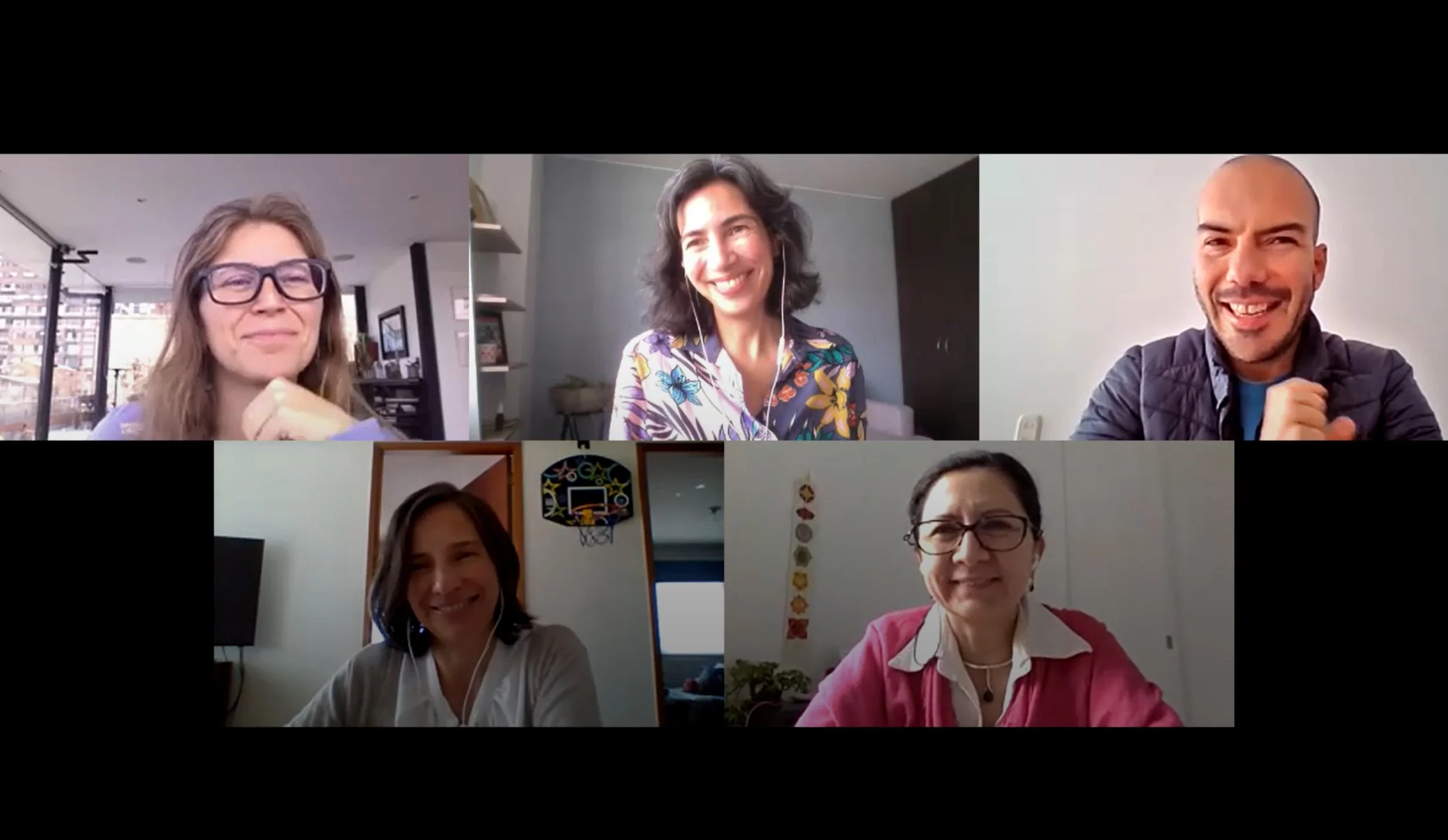 Cinco personas en videollamada, sonriendo y usando audífonos, en diferentes ambientes interiores con decoraciones variadas.