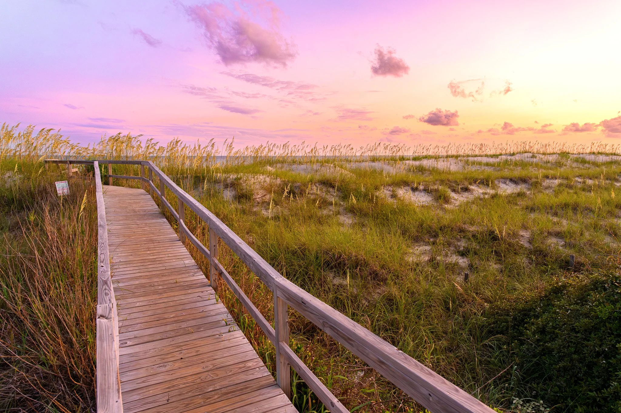 Boardwalk through coastal dunes at sunset on Bald Head Island, North Carolina.