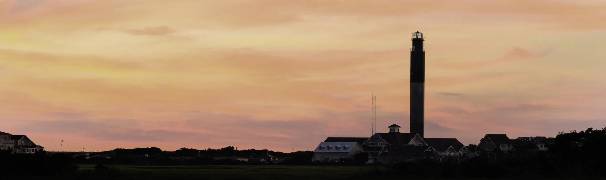 Oak Island Lighthouse at sunset overlooking Caswell Beach on Oak Island, North Carolina.