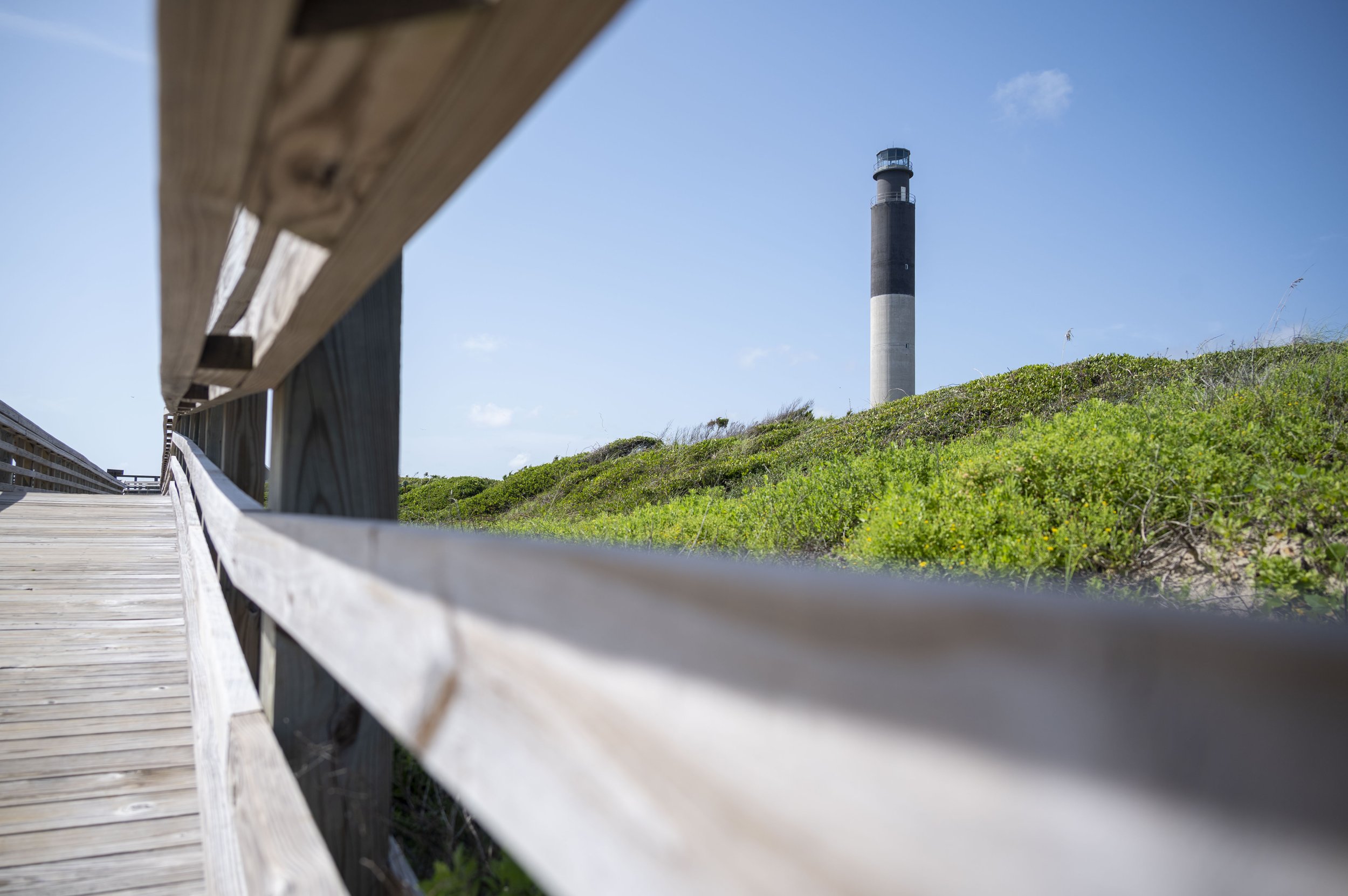Boardwalk leading toward the Oak Island Lighthouse and coastal dunes on Oak Island, North Carolina.