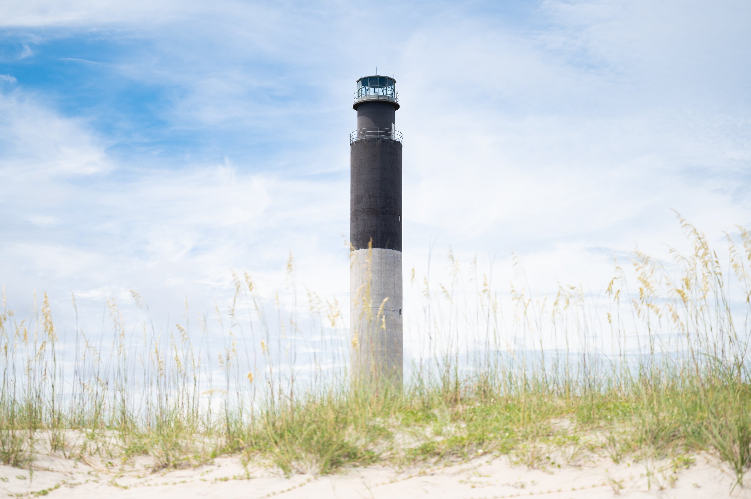 Oak Island Lighthouse rising above sea oats and sand dunes near Caswell Beach on Oak Island, North Carolina.