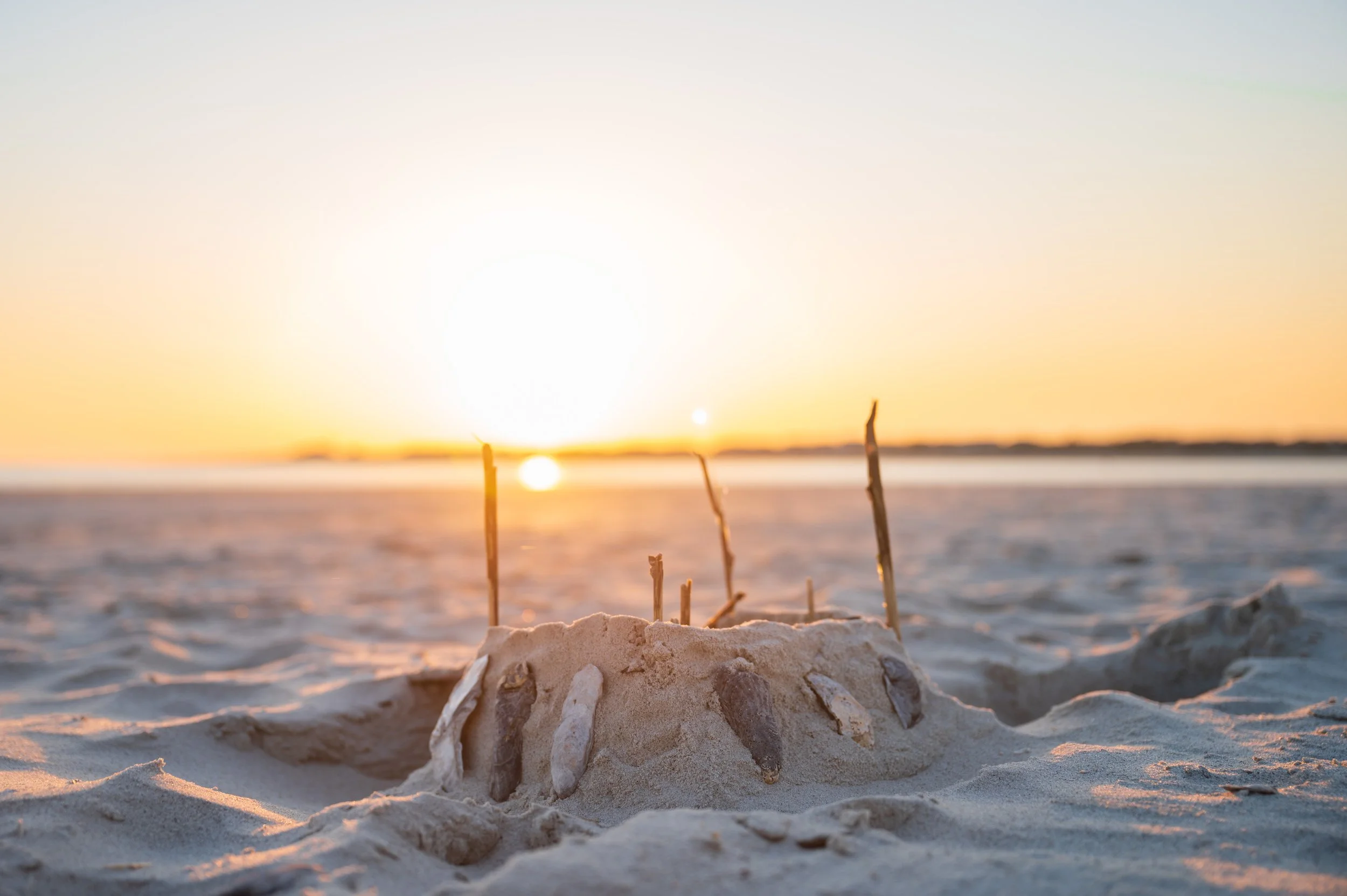 Sunset over The Point on Oak Island, North Carolina, where visitors gather to watch the sun set along the shoreline.