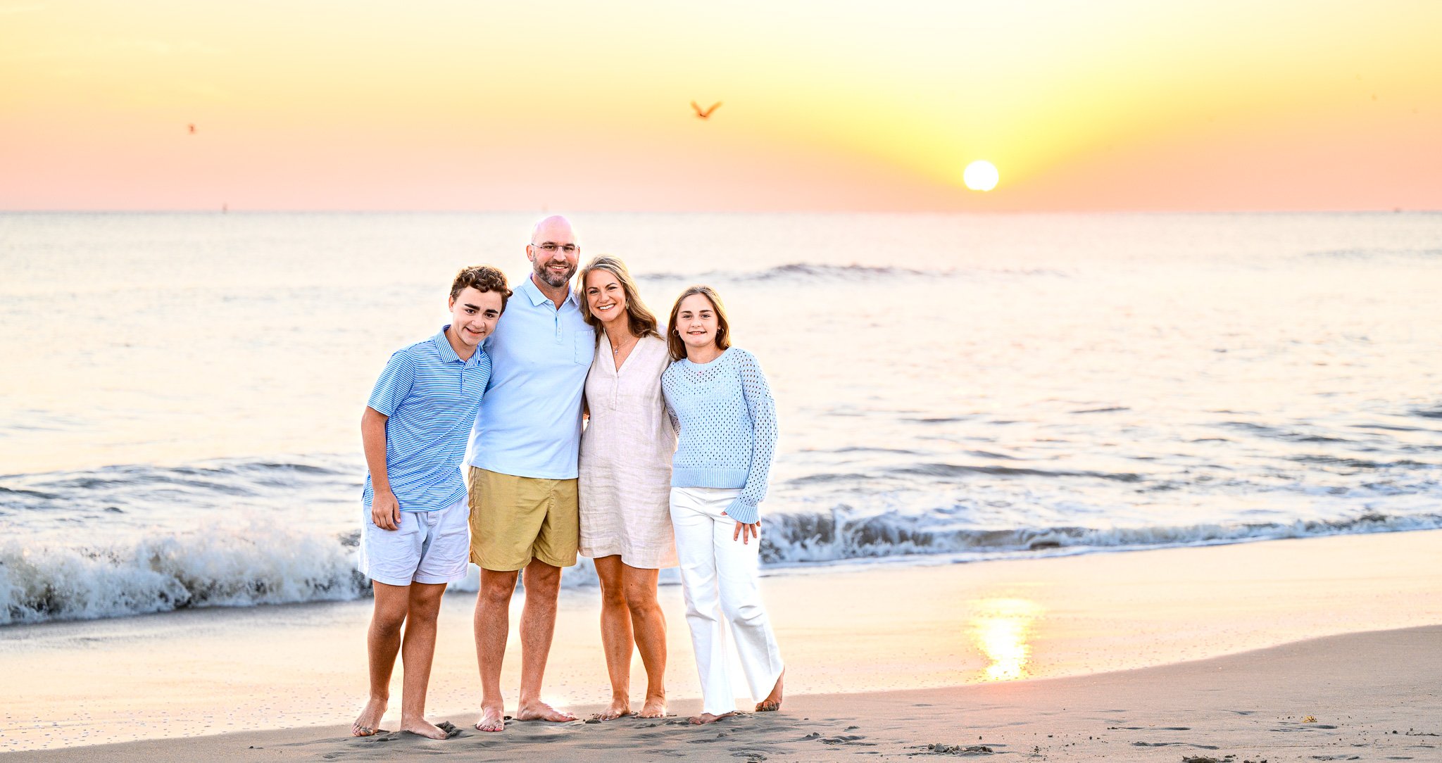 Family posing for sunset beach photos on Oak Island, North Carolina.