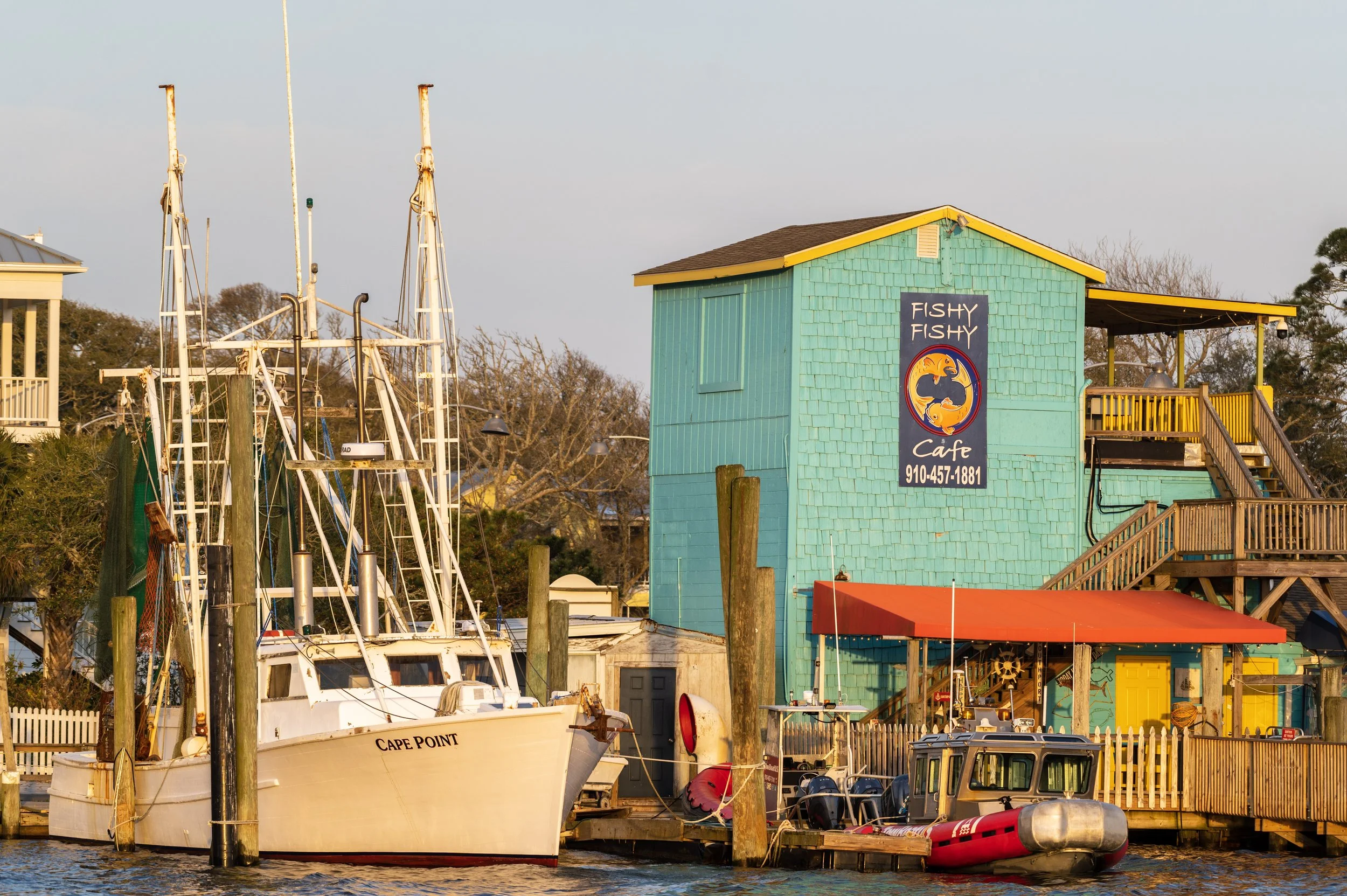Fishy Fishy Cafe and commercial fishing boats along the Southport waterfront at sunset.