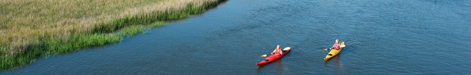 Kayakers paddling through the marshes and waterways of Davis Canal on Oak Island, North Carolina.