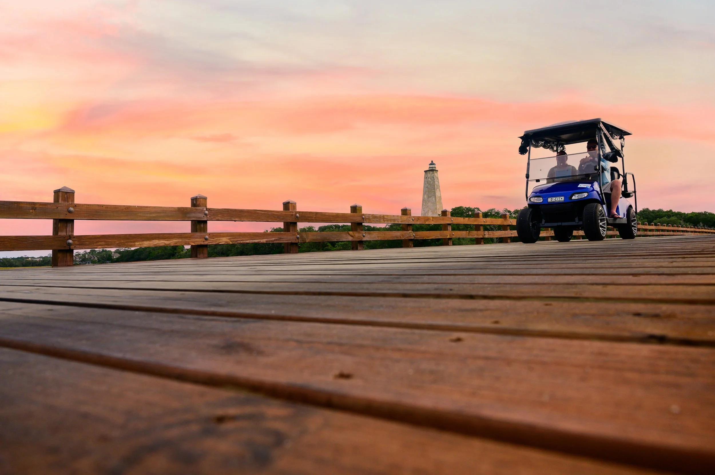 Golf cart crossing the Old Baldy boardwalk at sunset on Bald Head Island, North Carolina.