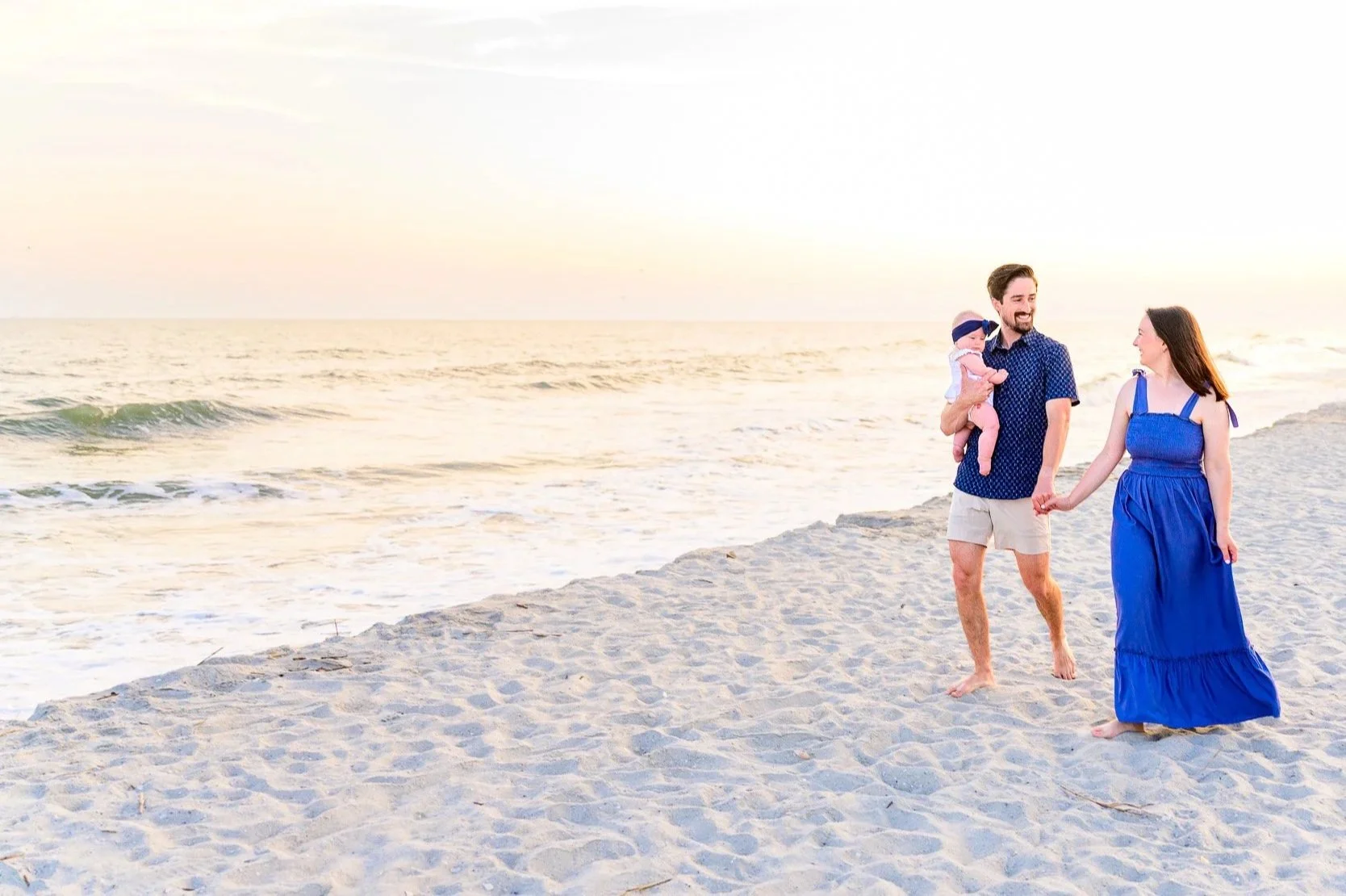 Family walking along the beach during a sunset photo session on Oak Island, North Carolina.