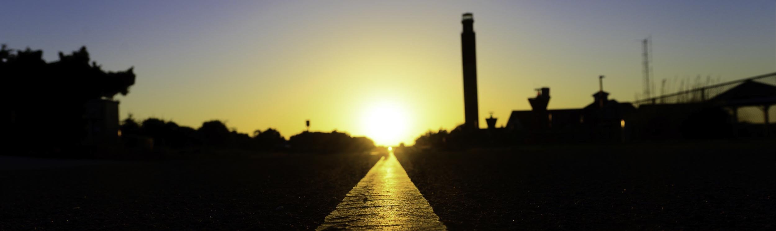 Sun setting behind the Oak Island Lighthouse at Caswell Beach on Oak Island, North Carolina.