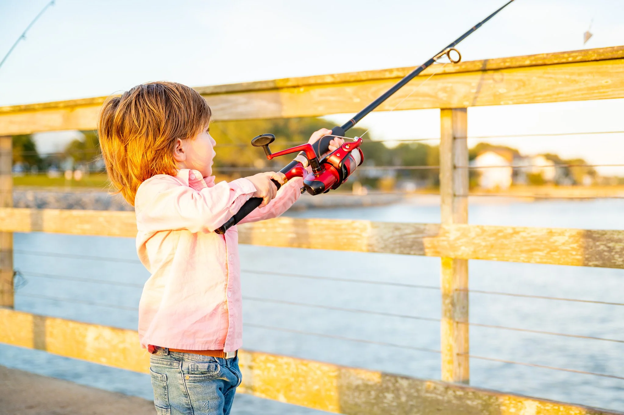 Young child fishing from Oak Island Pier during golden hour on Oak Island, North Carolina.