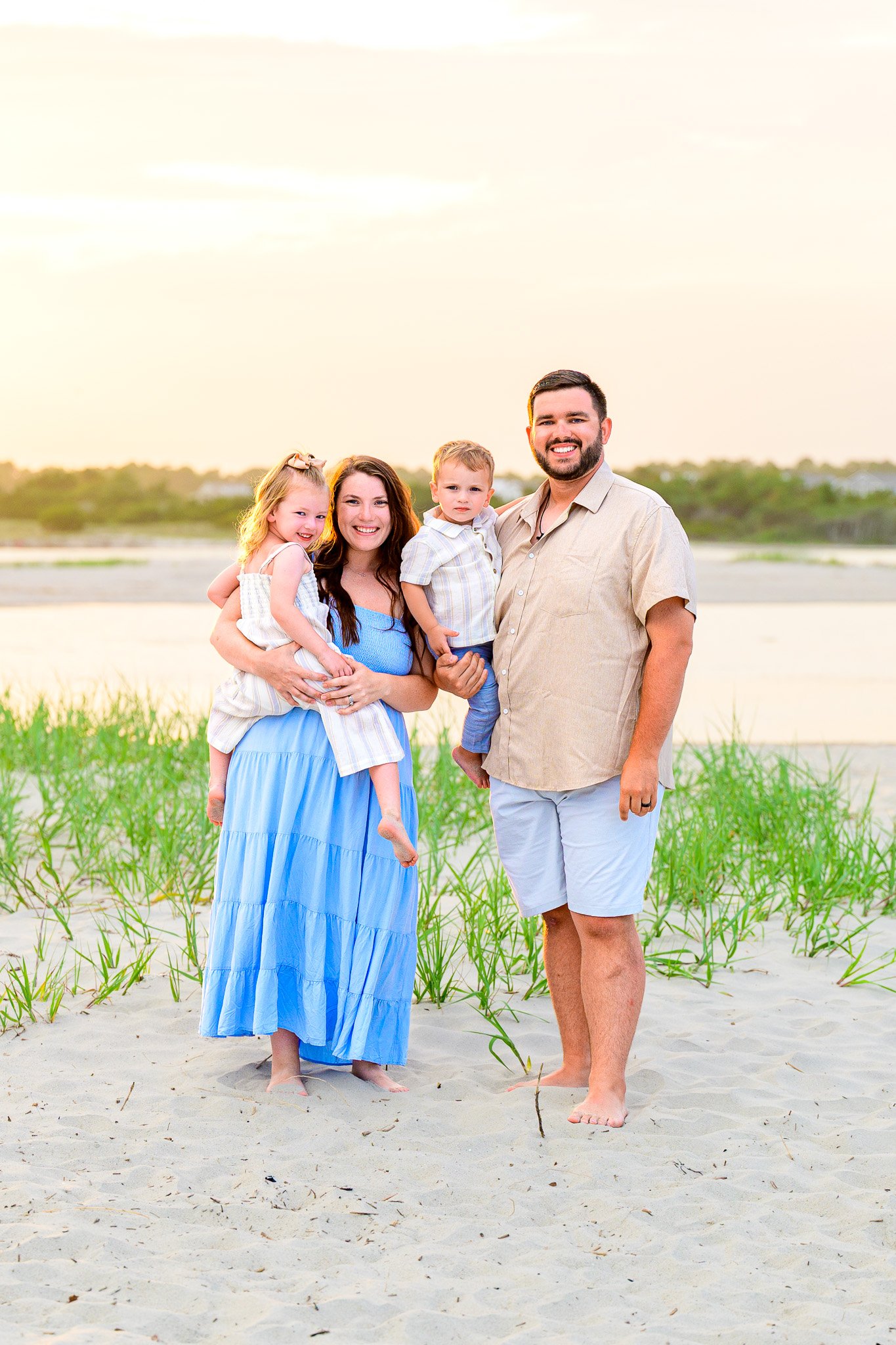 Family posing for vacation photos at The Point on Oak Island, North Carolina during a golden hour beach photography session.